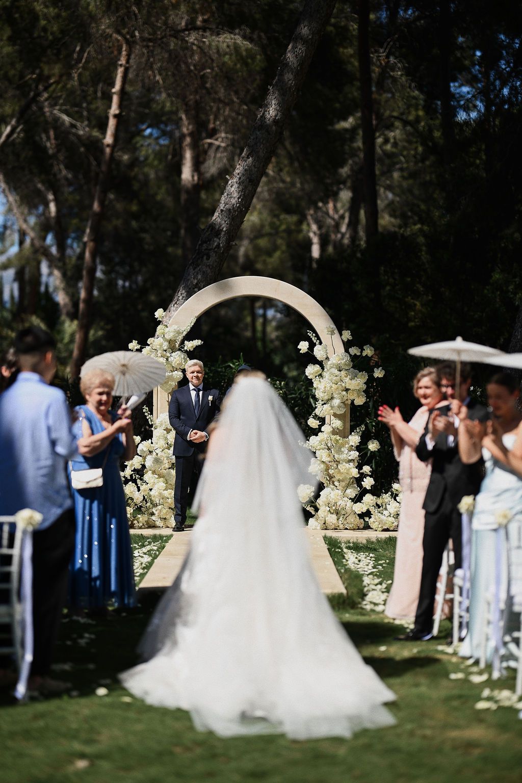 Emotional entrance of the bride with a long dress train walking towards the altar at Finca El Senyoret wedding in Benidorm, Spain.