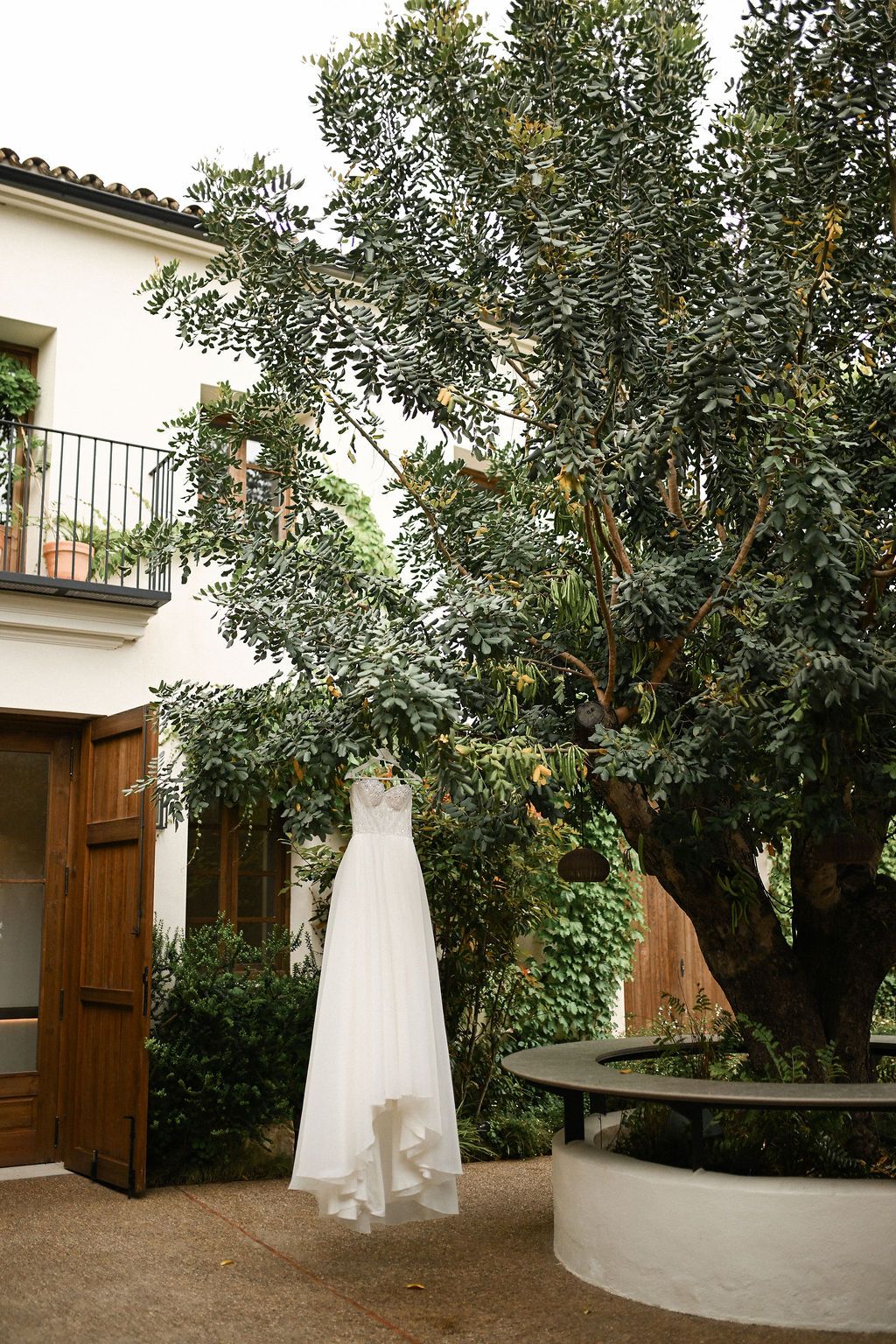 Luxury wedding dress captured by a professional wedding photographer in Valencia, hanging from a tree in the Finca del Canónigo garden.