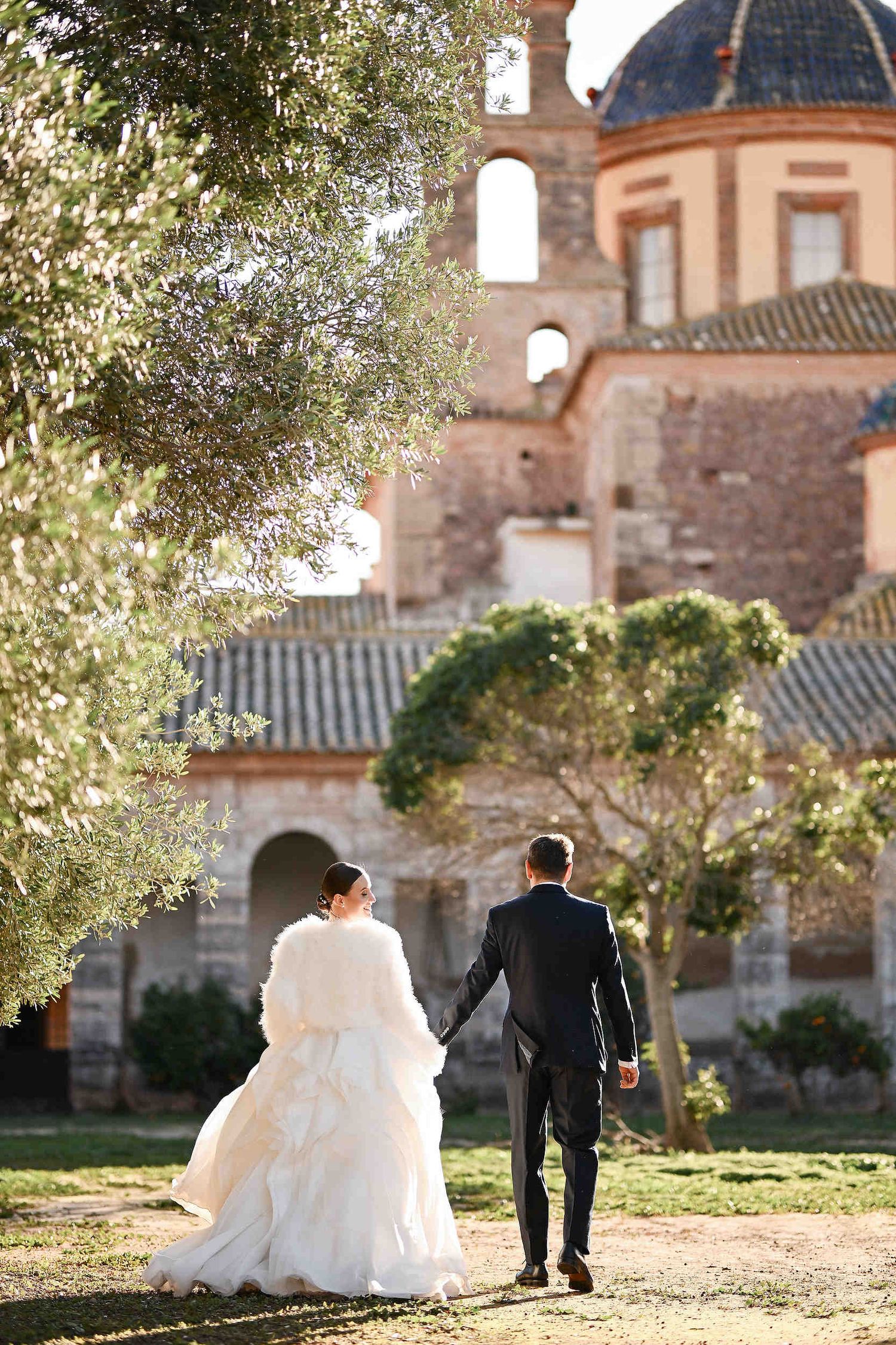 Bride and groom strolling through the lush olive gardens of La Cartoixa d'Ara Christi, capturing the quintessential Valencian spirit.