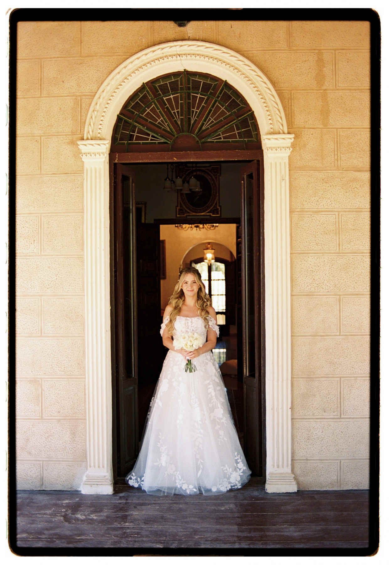 Bride smiling under an archway at Finca El Senyoret, captured by a Benidorm film wedding photographer.