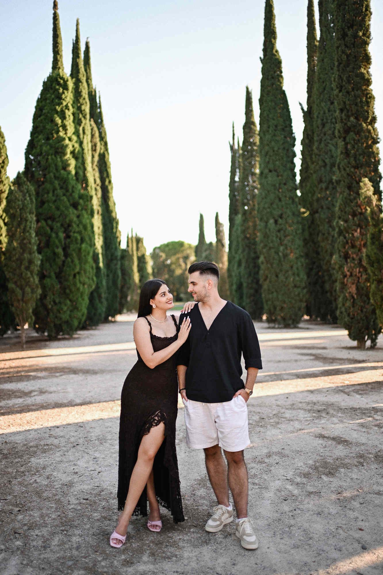 Proposal photographer in Valencia captures a newly engaged couple standing between tall cypress trees.