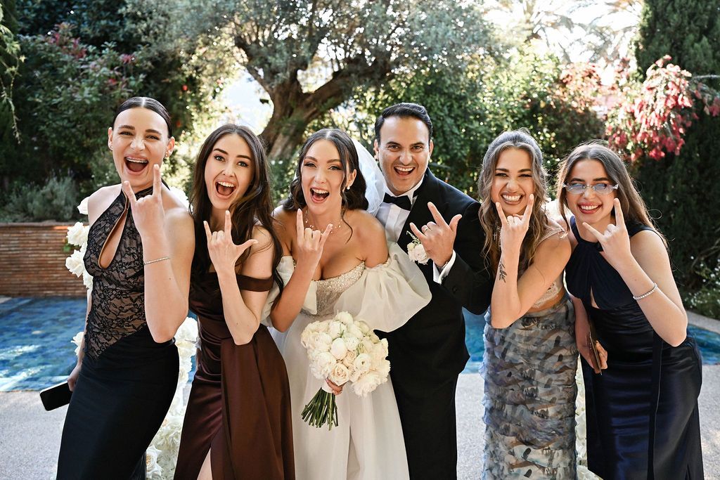 An emotional and candid photo of the bride, groom, and bridesmaids laughing together by the floral arch at Finca del Canónigo wedding.