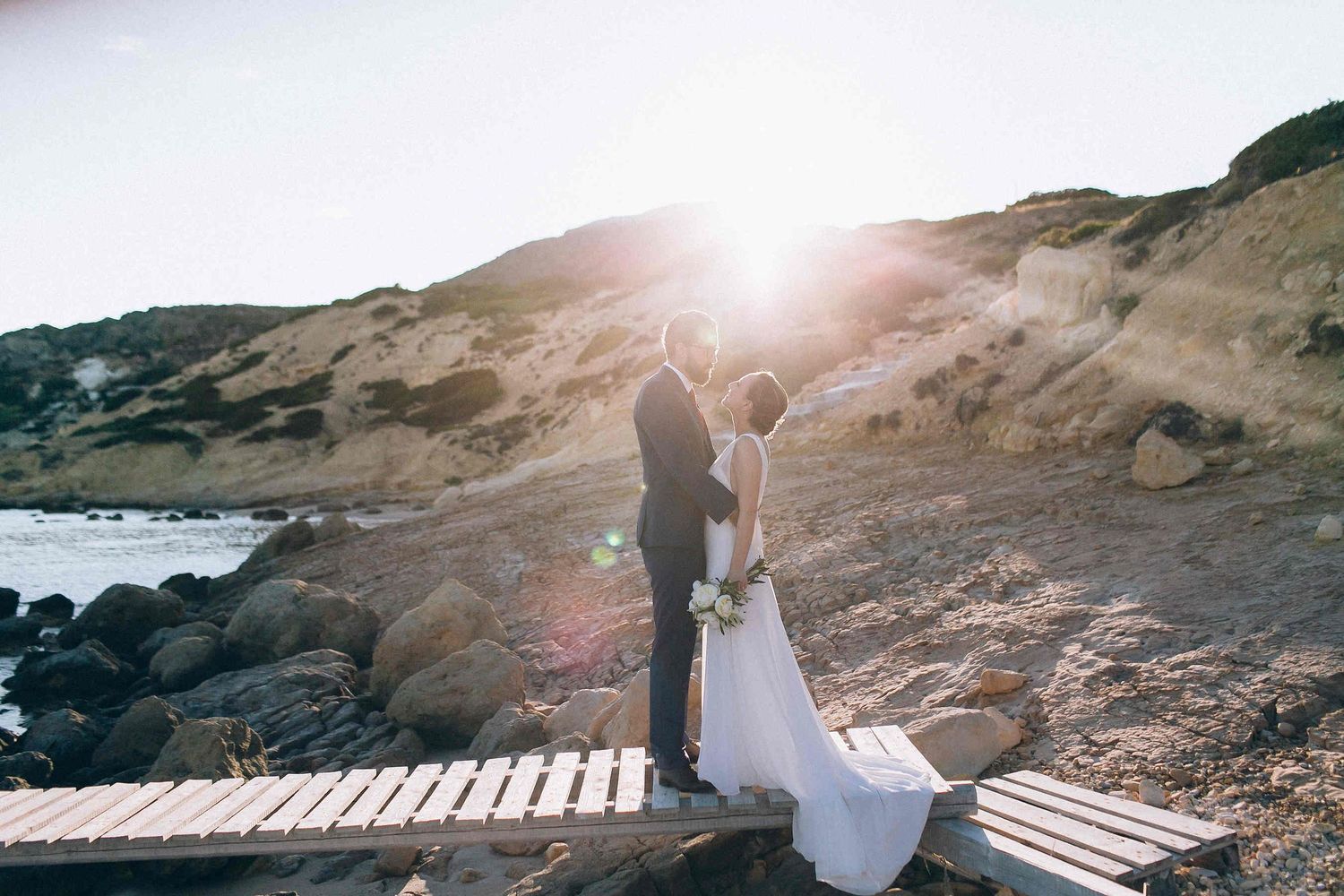 Authentic shot of the bride and groom standing on a traditional Greek wooden pier