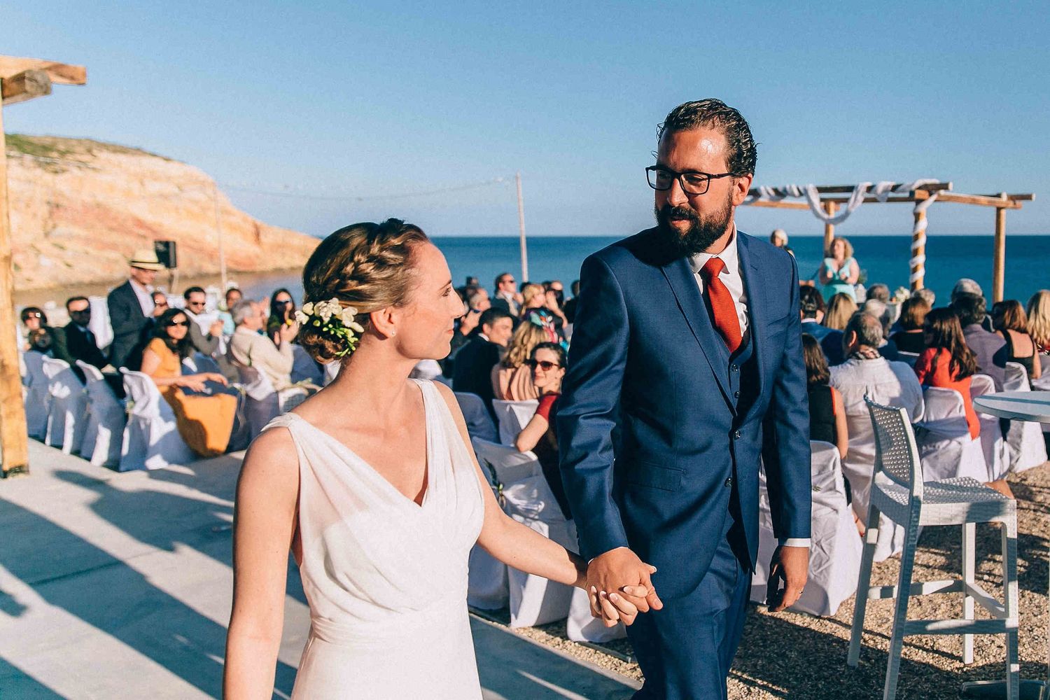 Happy just-married couple walking down the aisle after the ceremony in Milos.