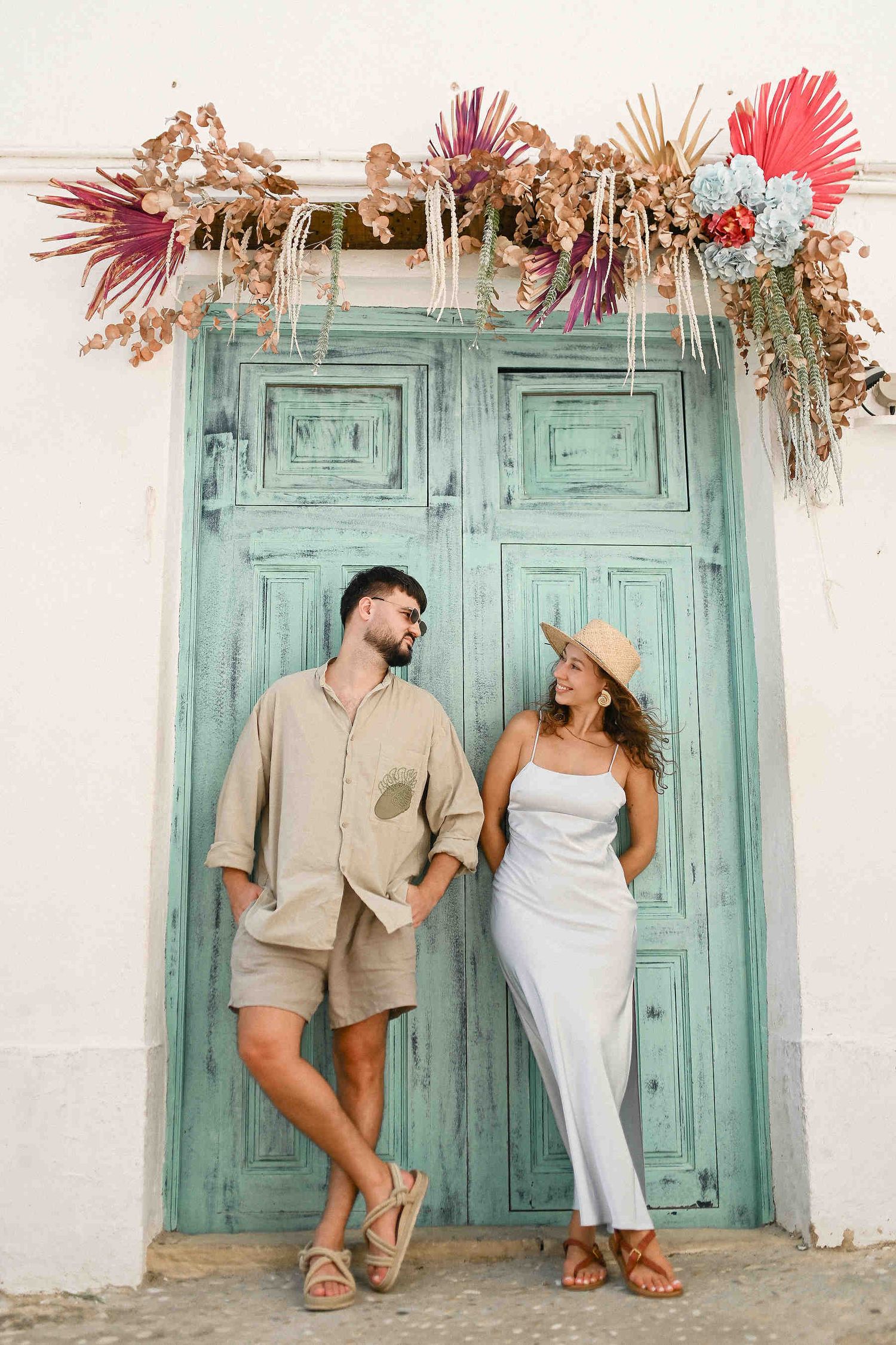 The couple posing elegantly by the iconic blue doors in the streets of Altea. High-fashion street aesthetic in a Spanish coastal town