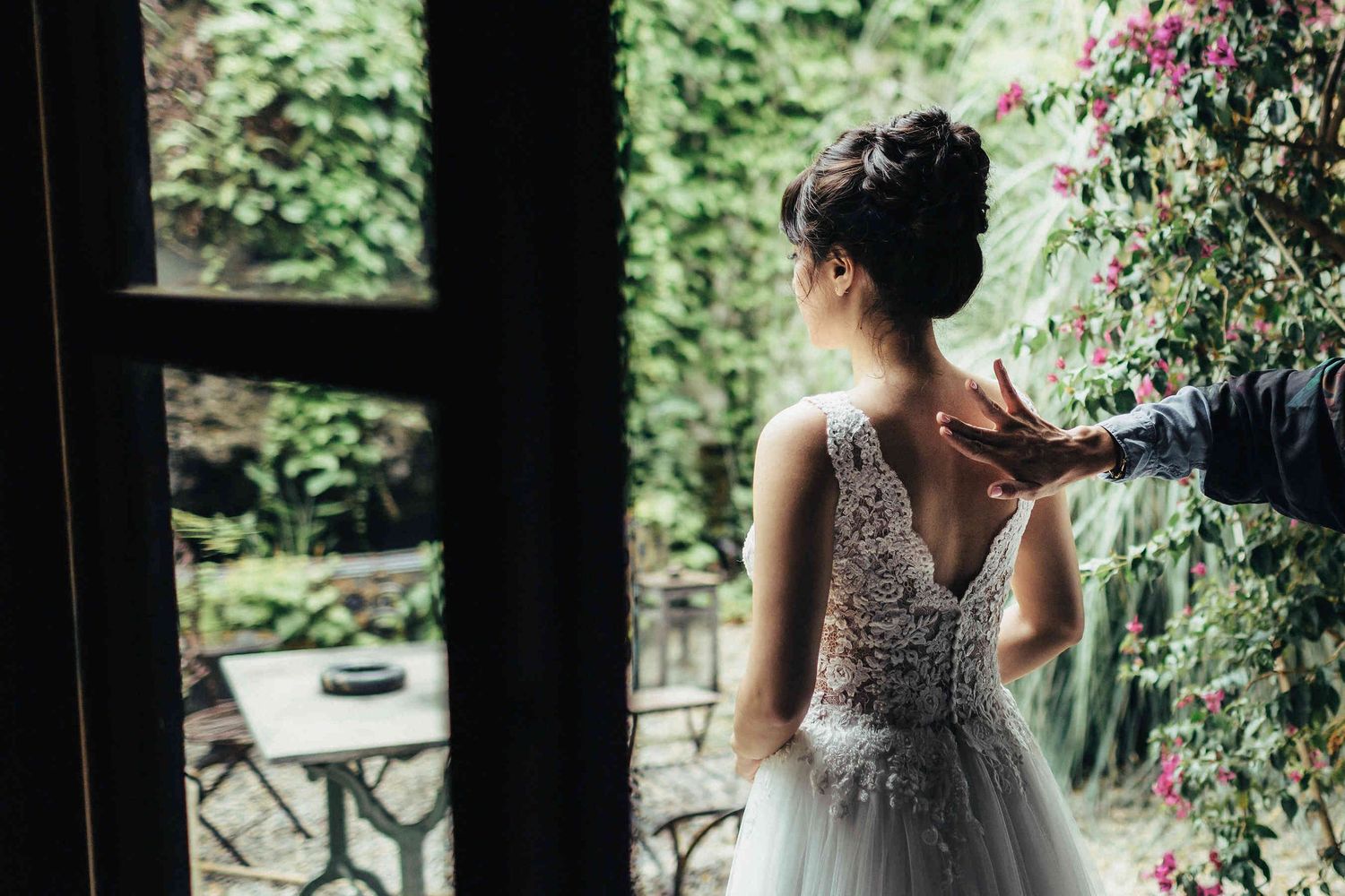 Bride’s morning preparations in Barcelona. Final makeup touches captured from behind, highlighting the elegant detail of the wedding dress