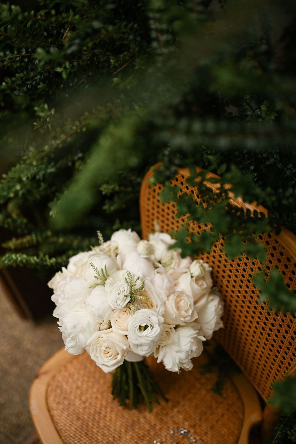 Elegant bridal bouquet with lush peony roses placed against the historic stone exterior of Finca del Canónigo venue in Valencia.