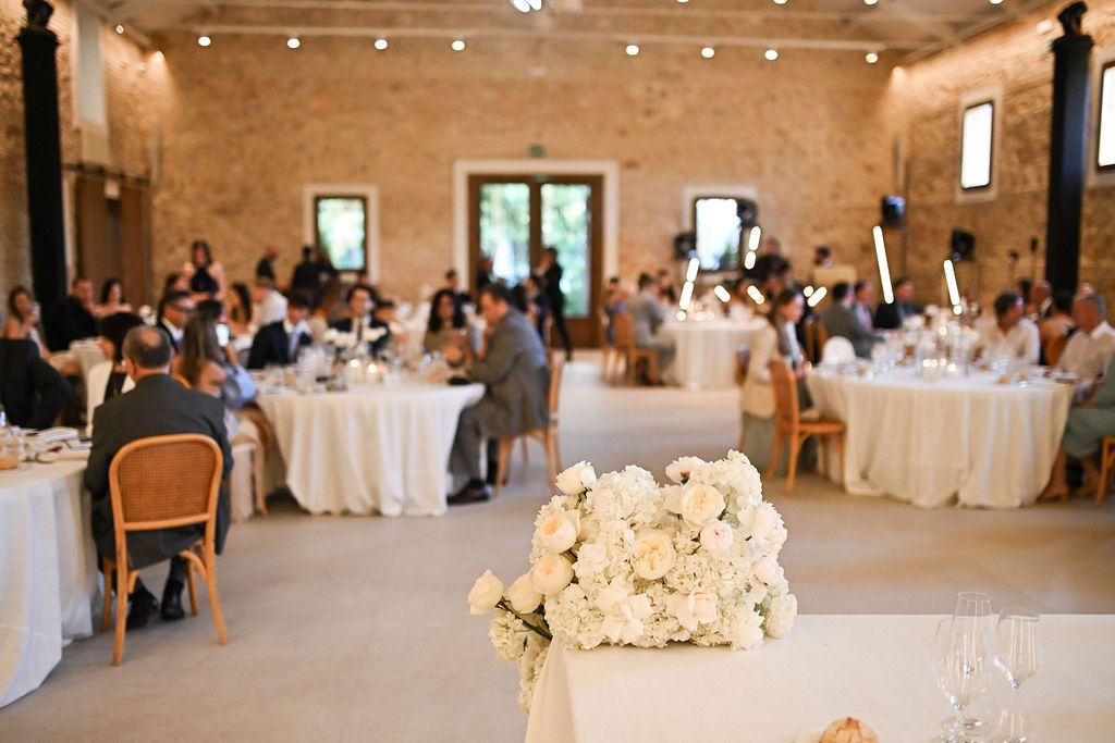 Lush floral decor on the newlyweds' table, showcasing the trendy circular seating layout inside the spacious Finca del Canónigo hall.