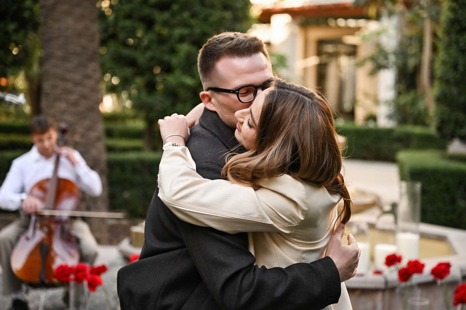 Newly engaged couple hugging after a surprise proposal at The Westin Valencia courtyard with a live cellist.