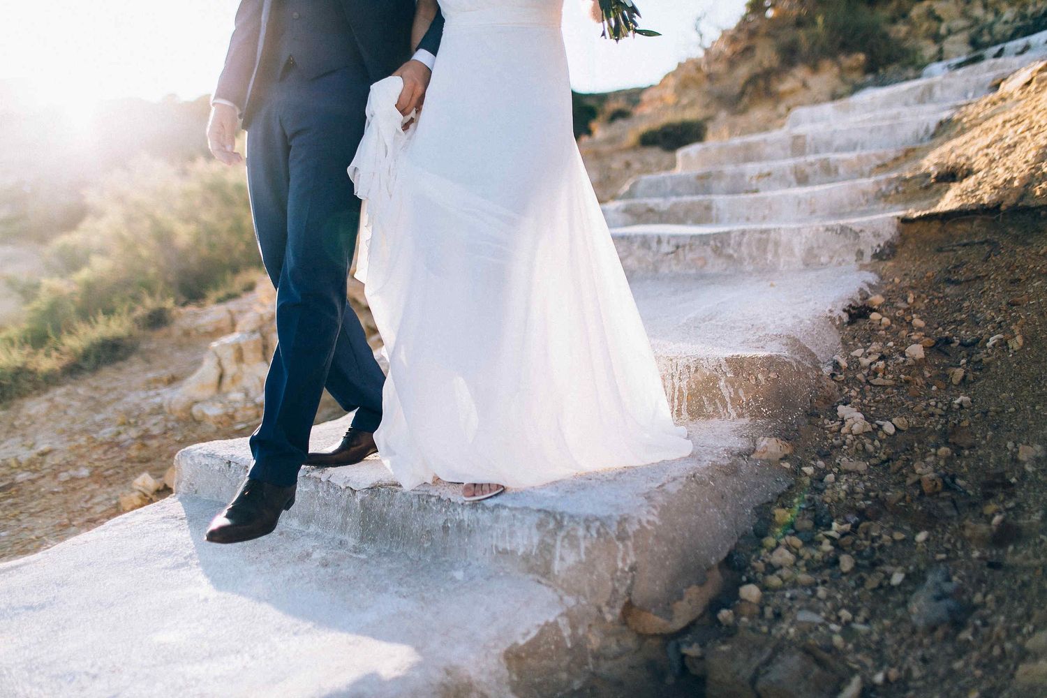 Atmospheric shot of the bride and groom's feet walking on the sandy beach of Milos