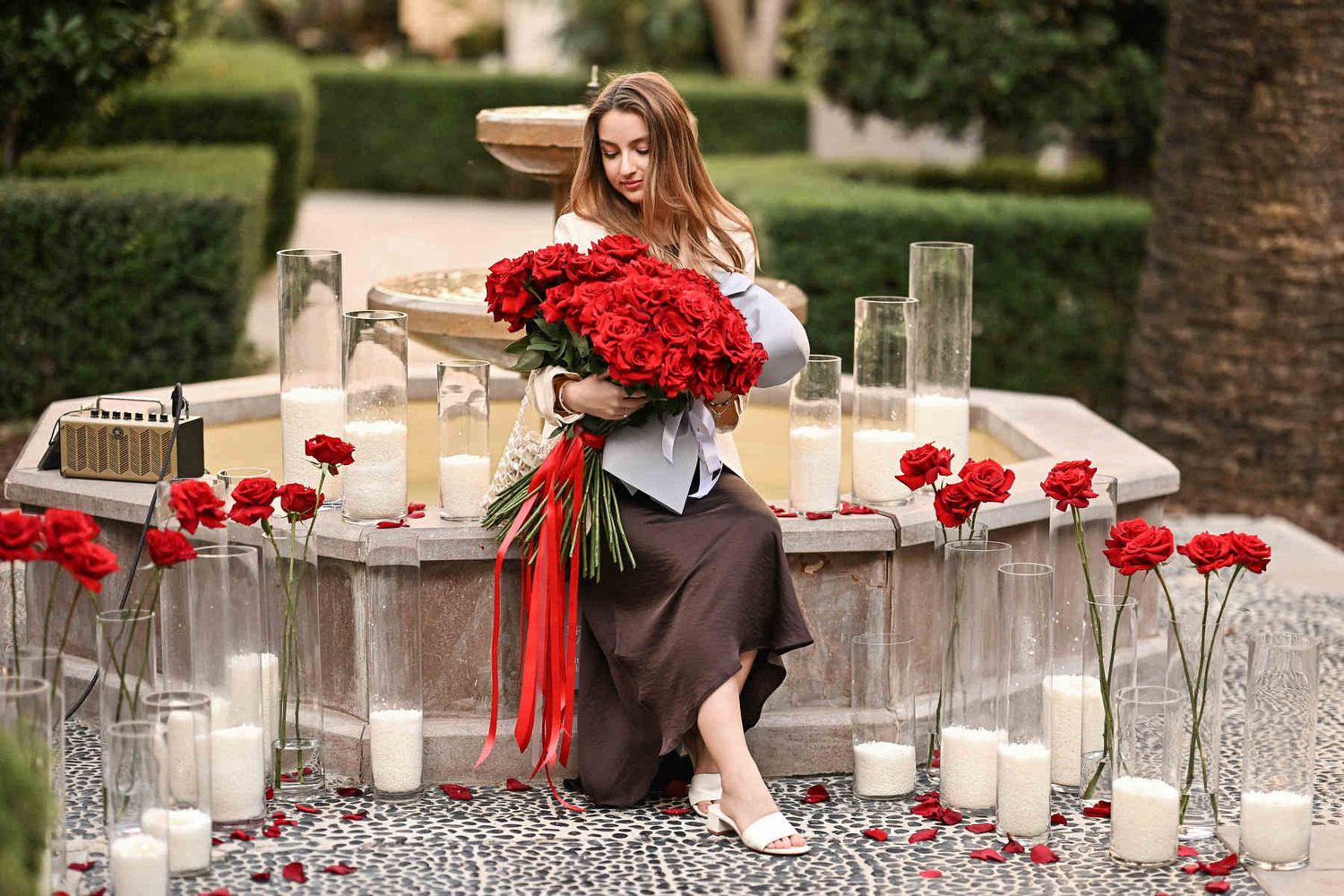 Newly engaged bride admiring her huge red rose bouquet by the fountain after a romantic proposal at The Westin Valencia.