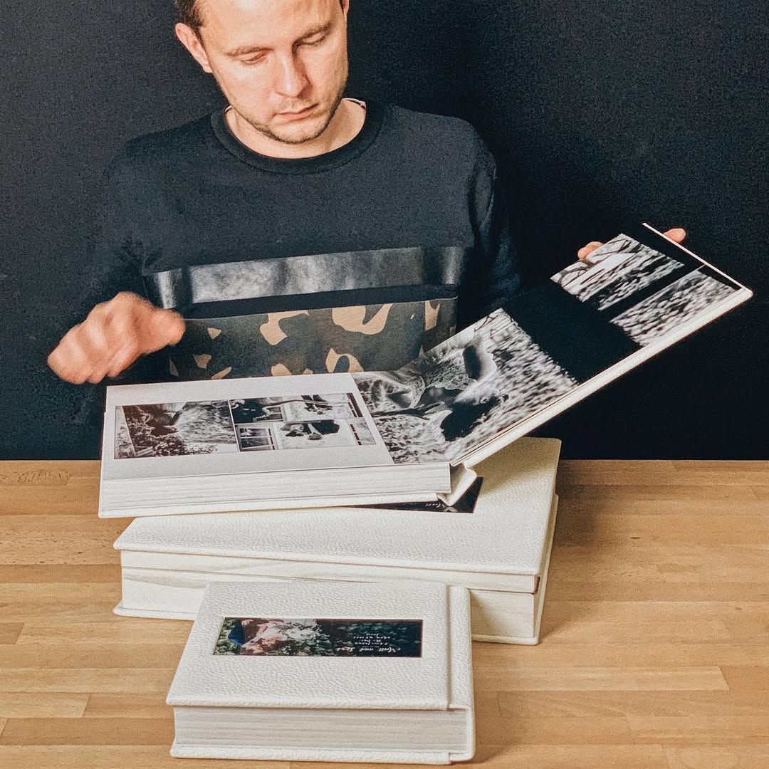 Photographer flipping through a custom wedding book featuring professional photography from a wedding in Barcelona, Spain.