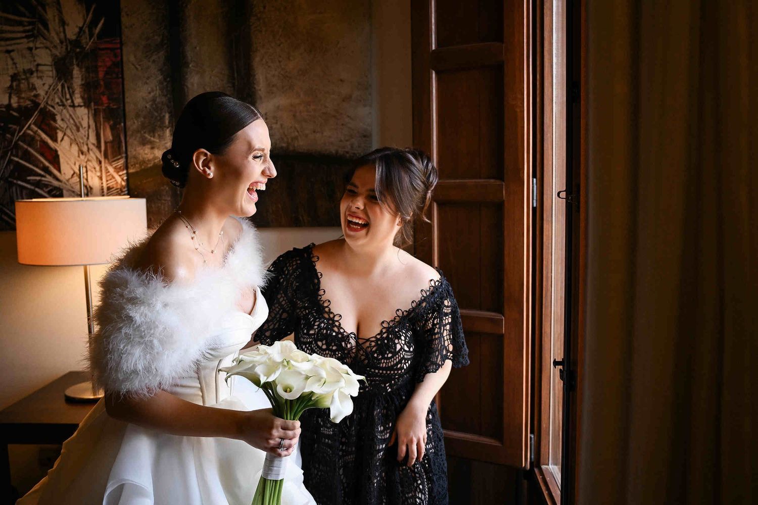 Candid documentary moment of a bride laughing with her bridesmaid during morning preparations at a destination wedding in Valencia.