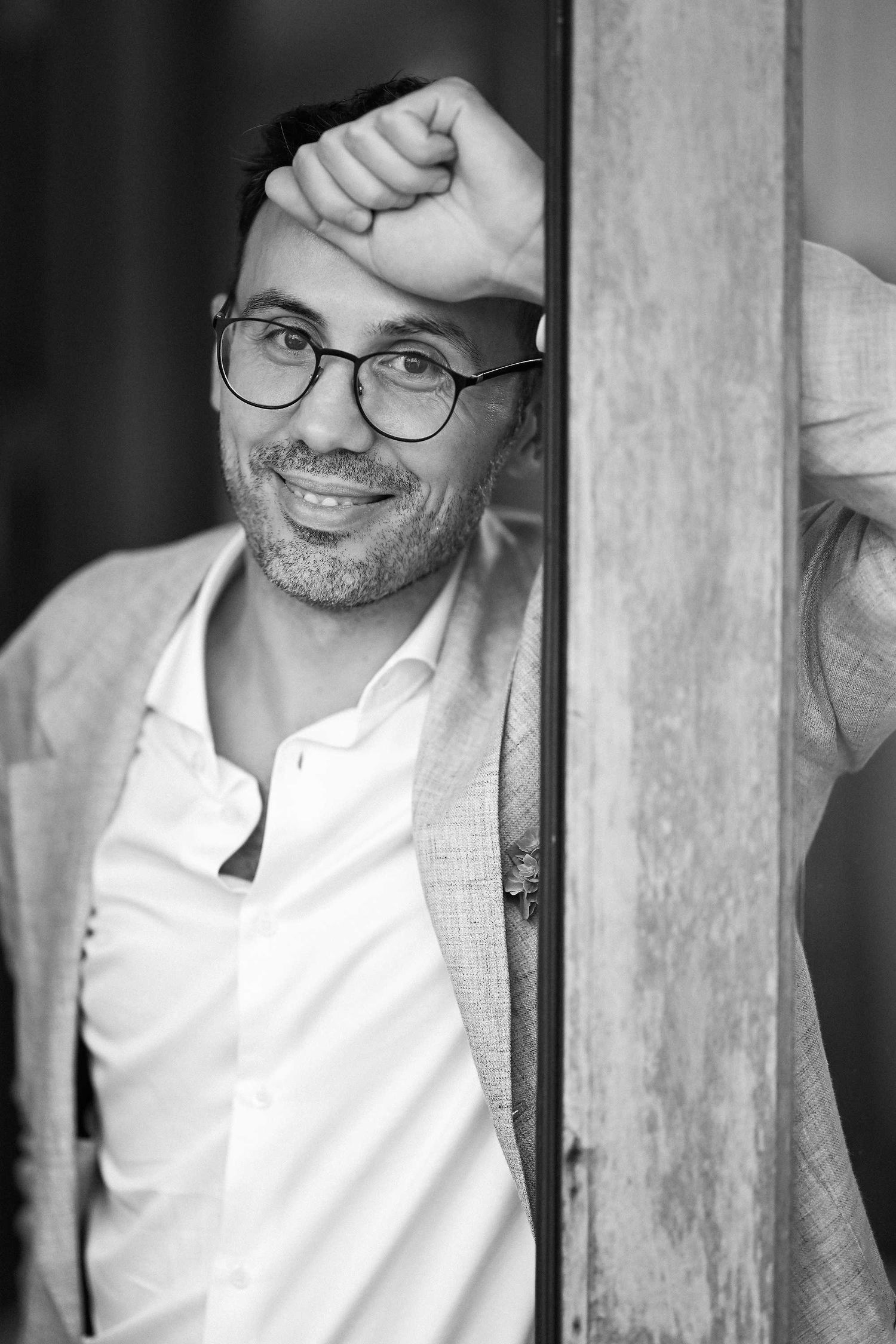 A classic black and white portrait of the groom, Semih, captured with a genuine smile during his wedding at Villa Paula