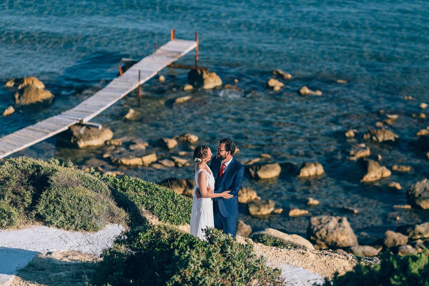 Modern wedding couple posing against the dramatic white volcanic cliffs and blue water