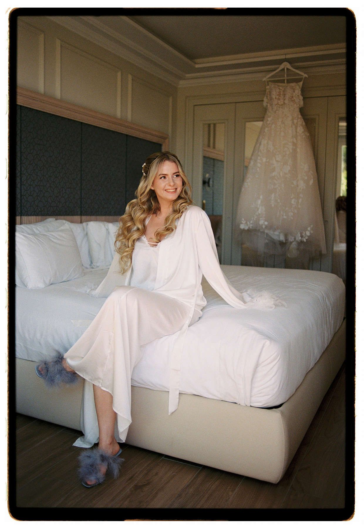 Smiling bride during morning prep with her wedding dress in the background, shot on Nikon F5 in Alicante.