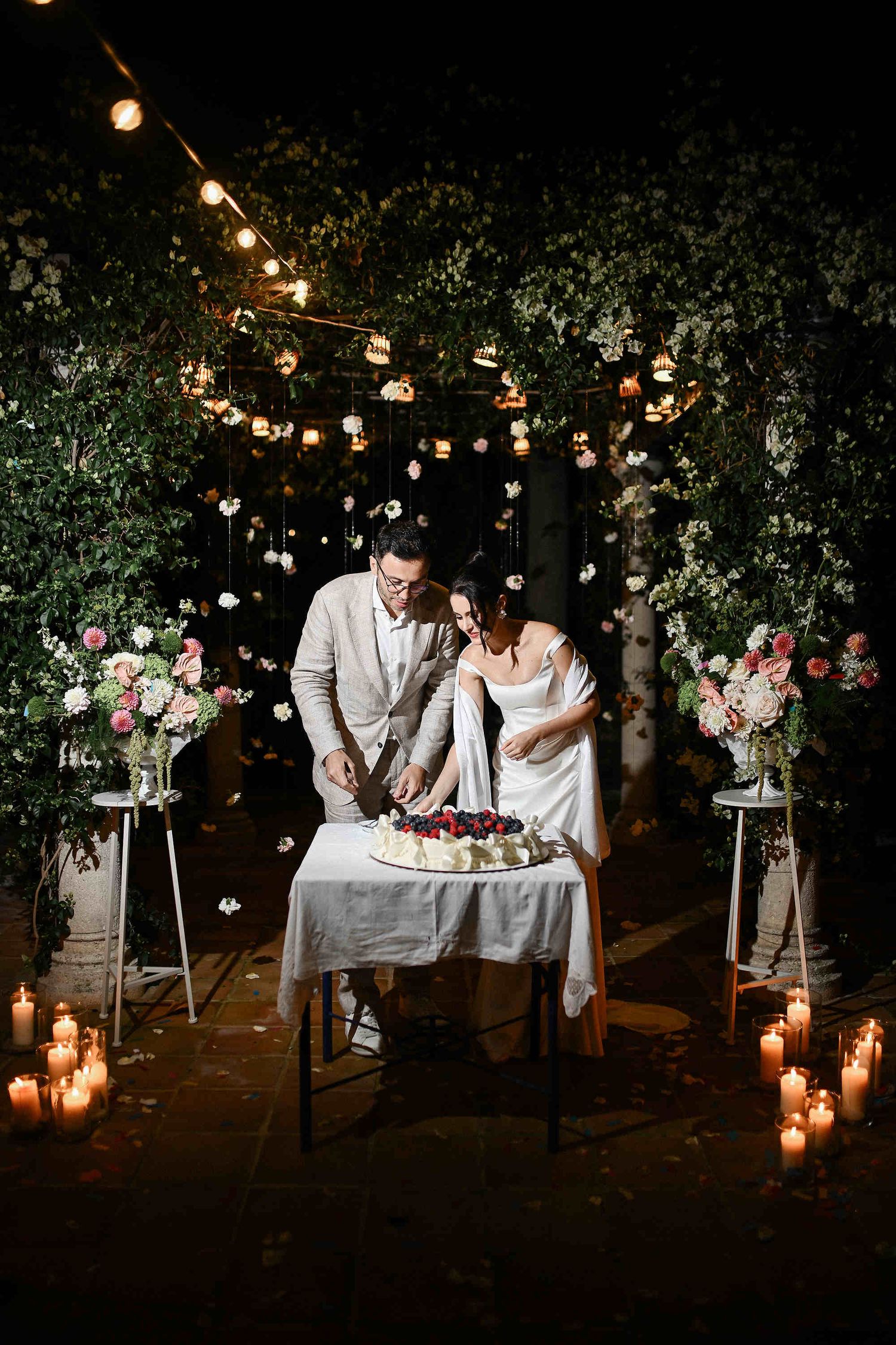 Wide shot of the wedding cake cutting ceremony at night, featuring bold direct flash at Villa Paula