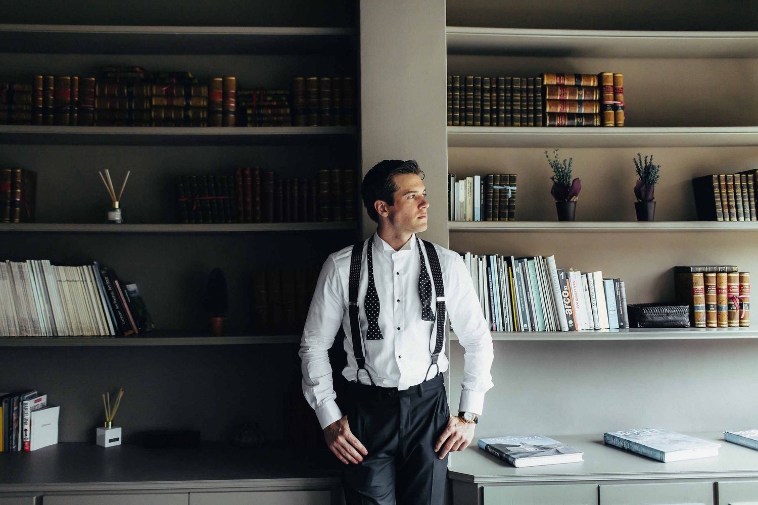 A cinematic shot of the groom getting dressed while looking out the window. Morning preparations at a historic villa near Barcelona