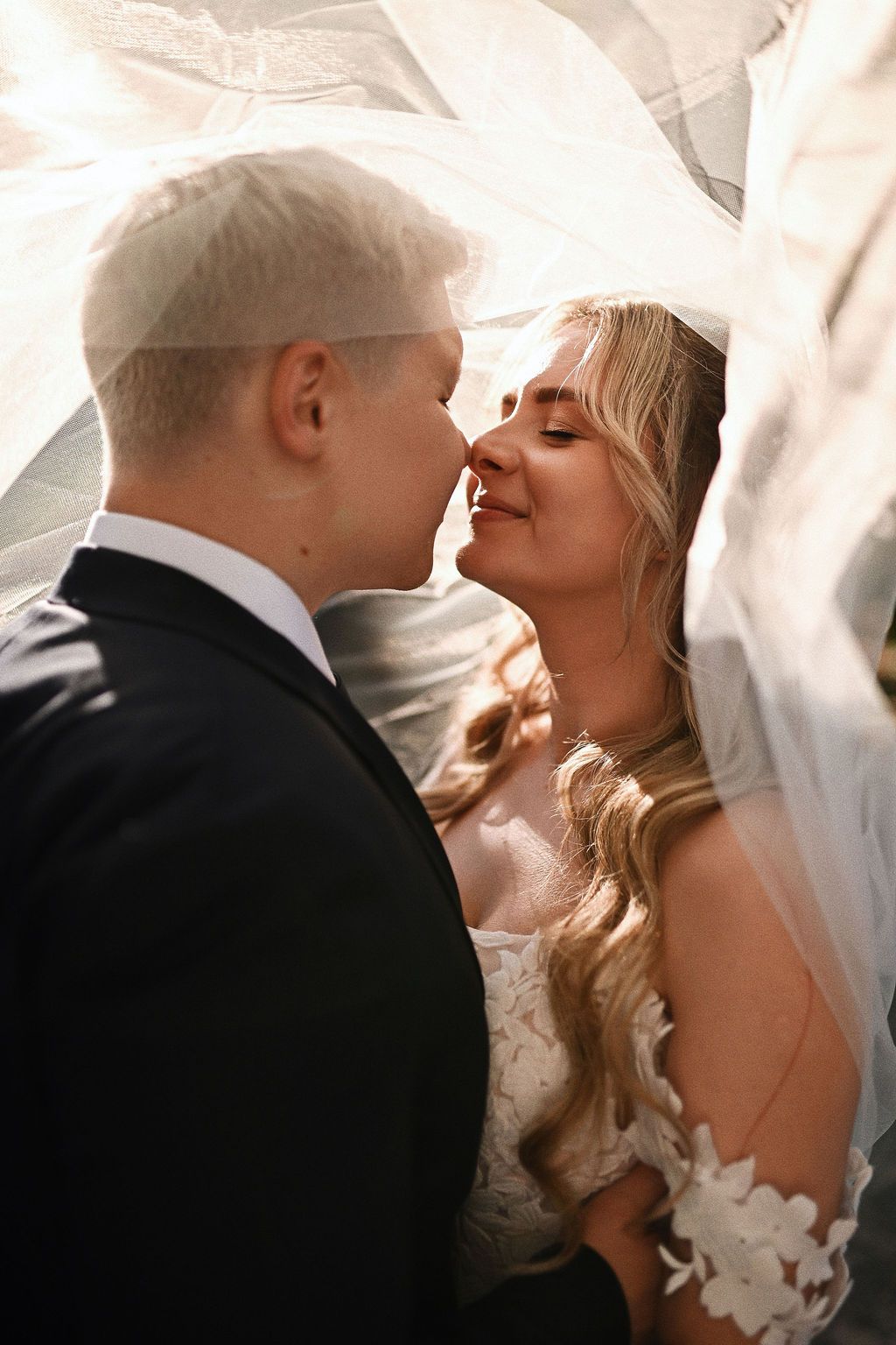 Artistic portrait of the bride and groom sharing a gentle kiss under the veil. Fine art wedding inspiration in Benidorm, Spain.