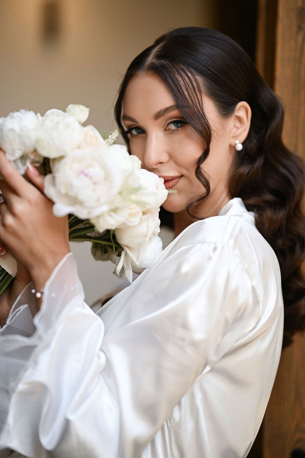 Close-up portrait of the bride wearing a delicate lace peignoir and holding her bouquet. Fine art wedding photography in Valencia, Spain.