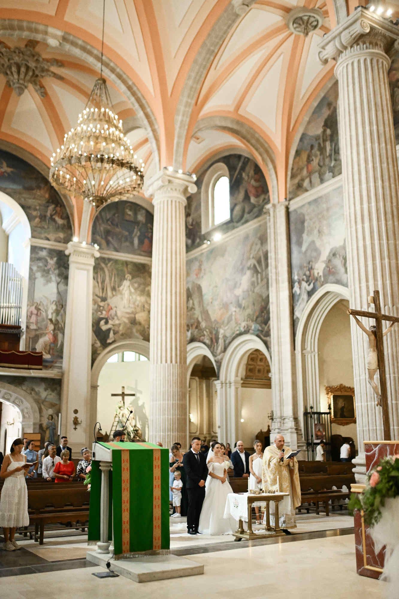 Documentary wedding photography of the bride, groom, and guests inside a beautiful Spanish church during the sacred ceremony.