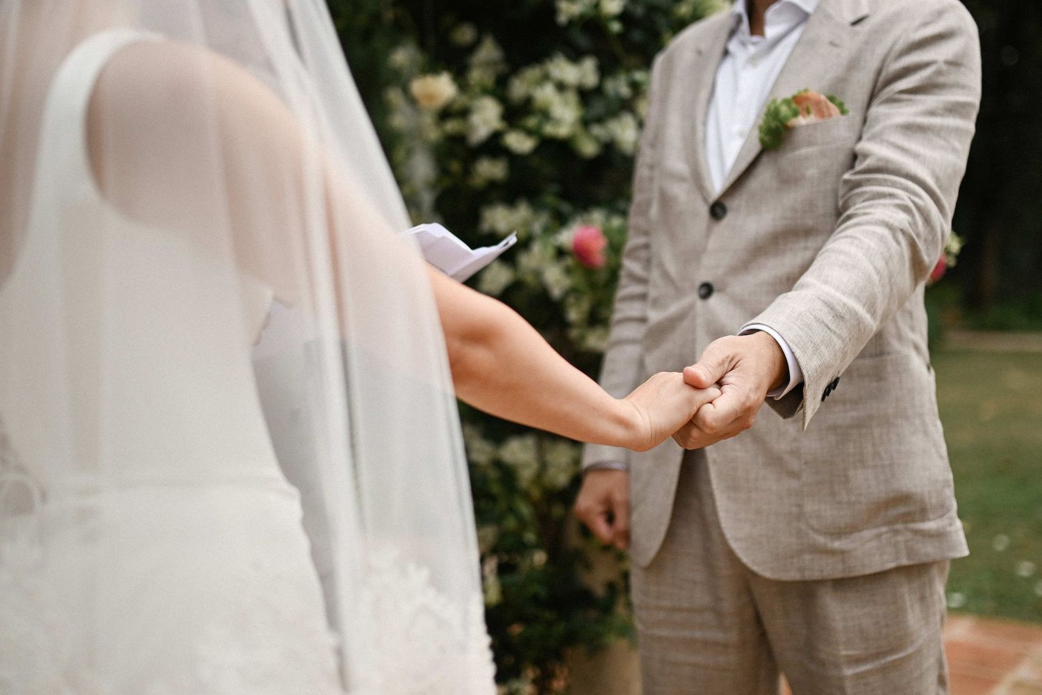A touching close-up shot of the groom holding the bride's hand during the wedding vows at Villa Paula