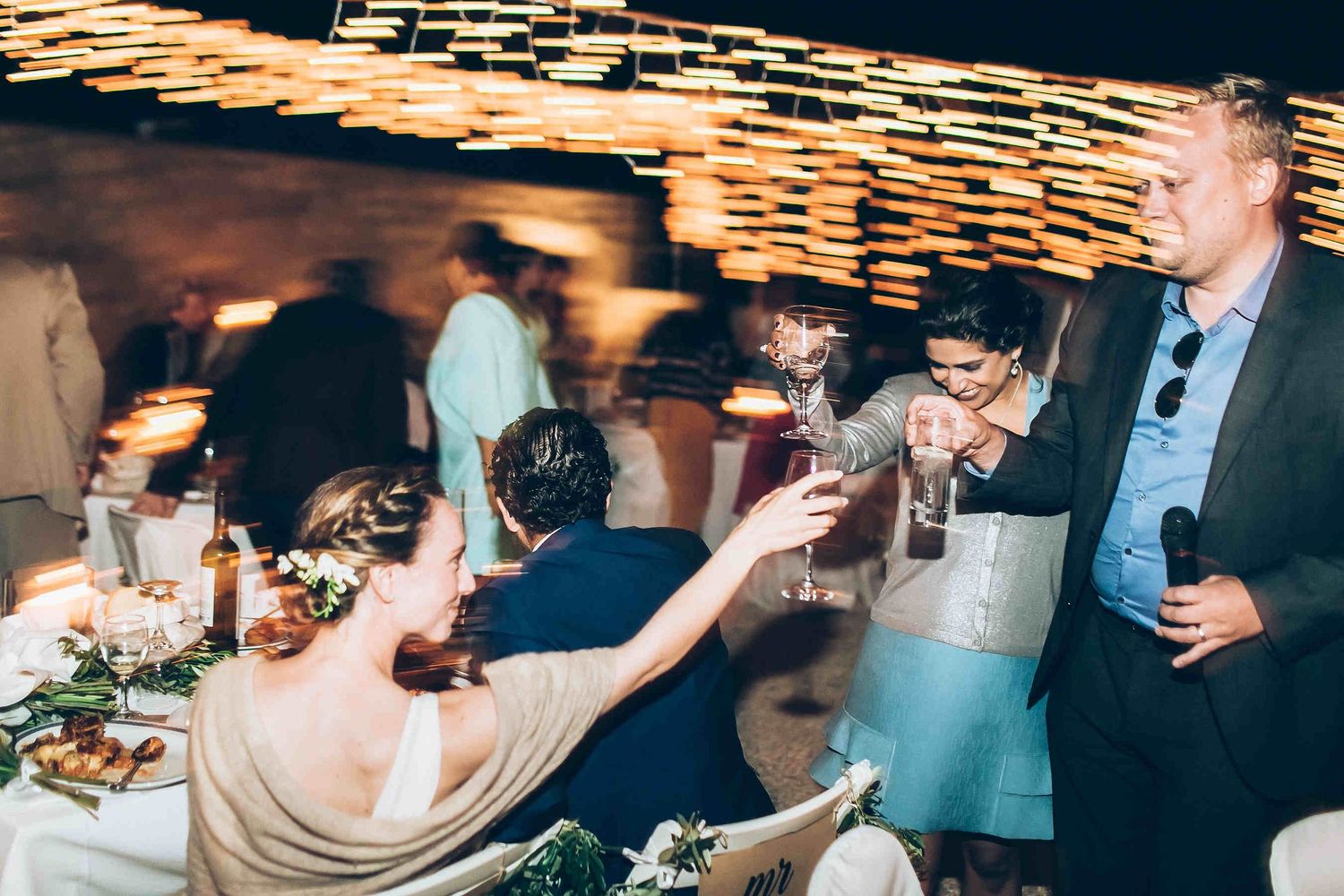Joyful moment of the bride clinking champagne glasses with her friends at the reception.