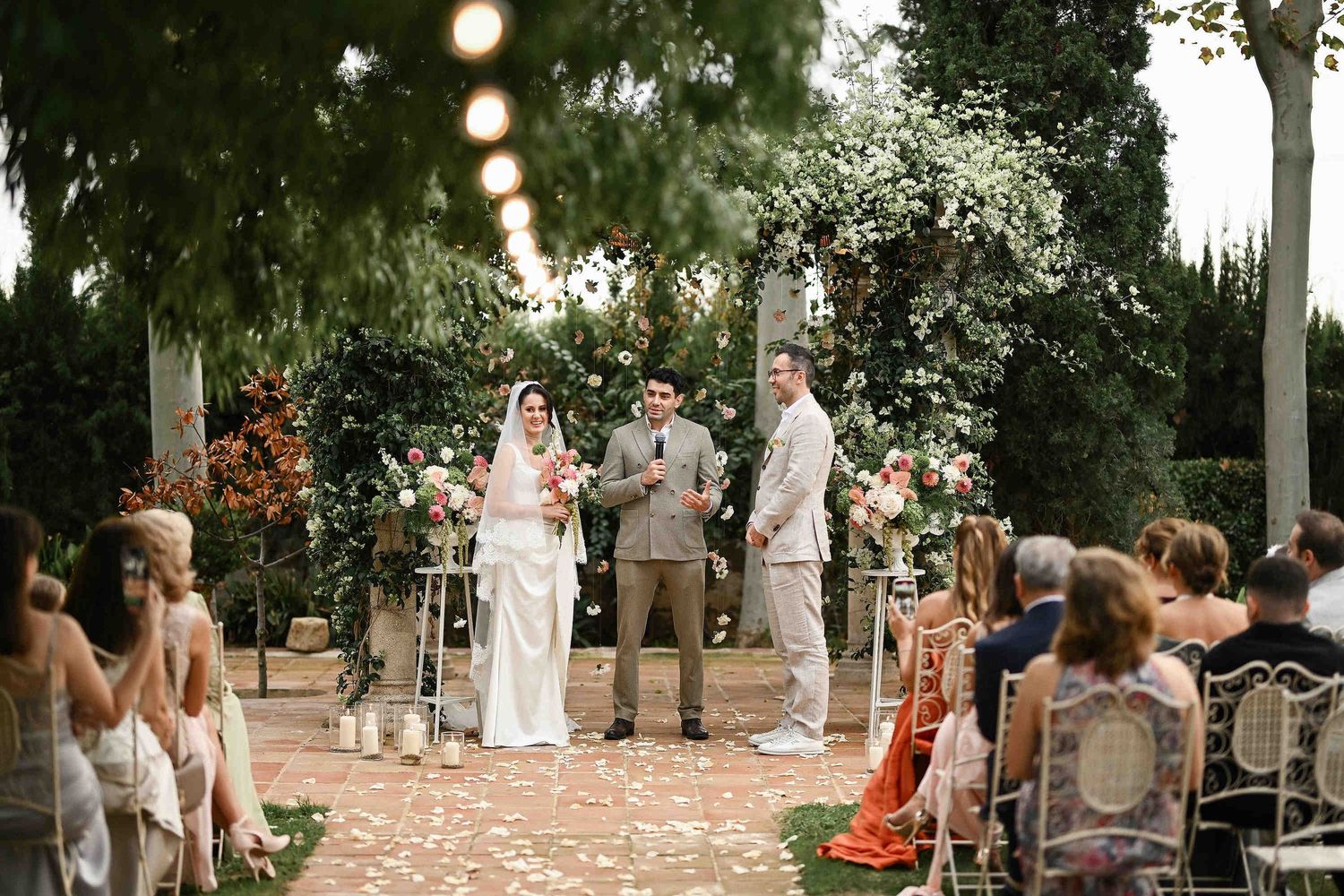 Emotional moment as the groom looks at the bride in front of a beautiful floral wedding arch during the ceremony