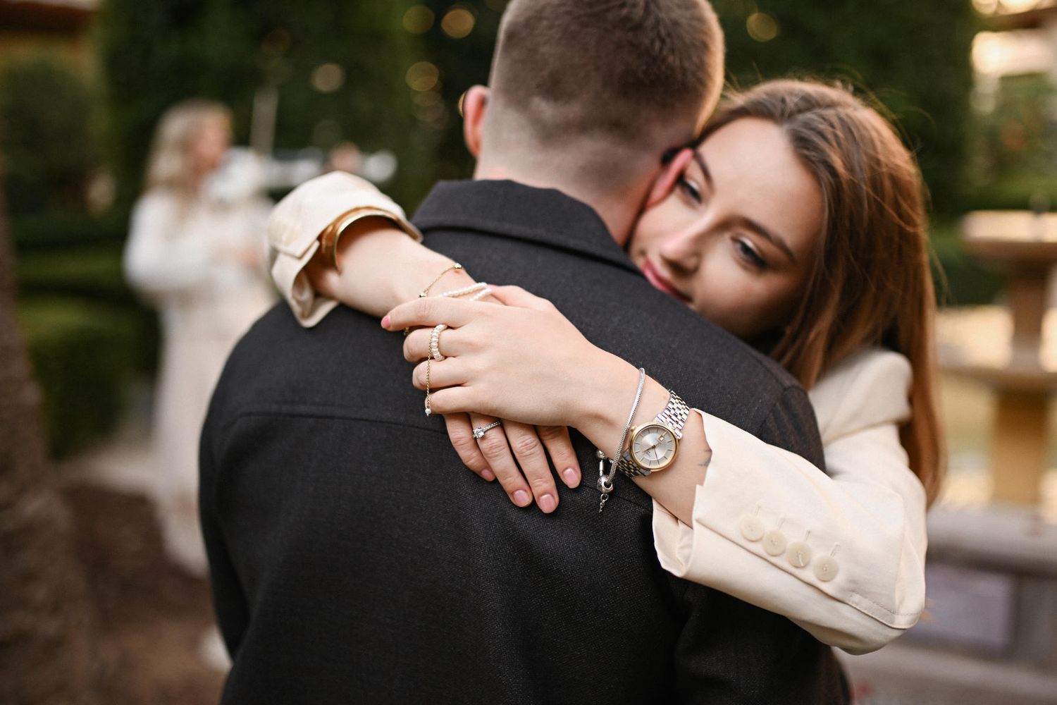 Close-up of an engaged woman hugging her fiancé, showing off her new diamond ring after their beautiful proposal in Spain.