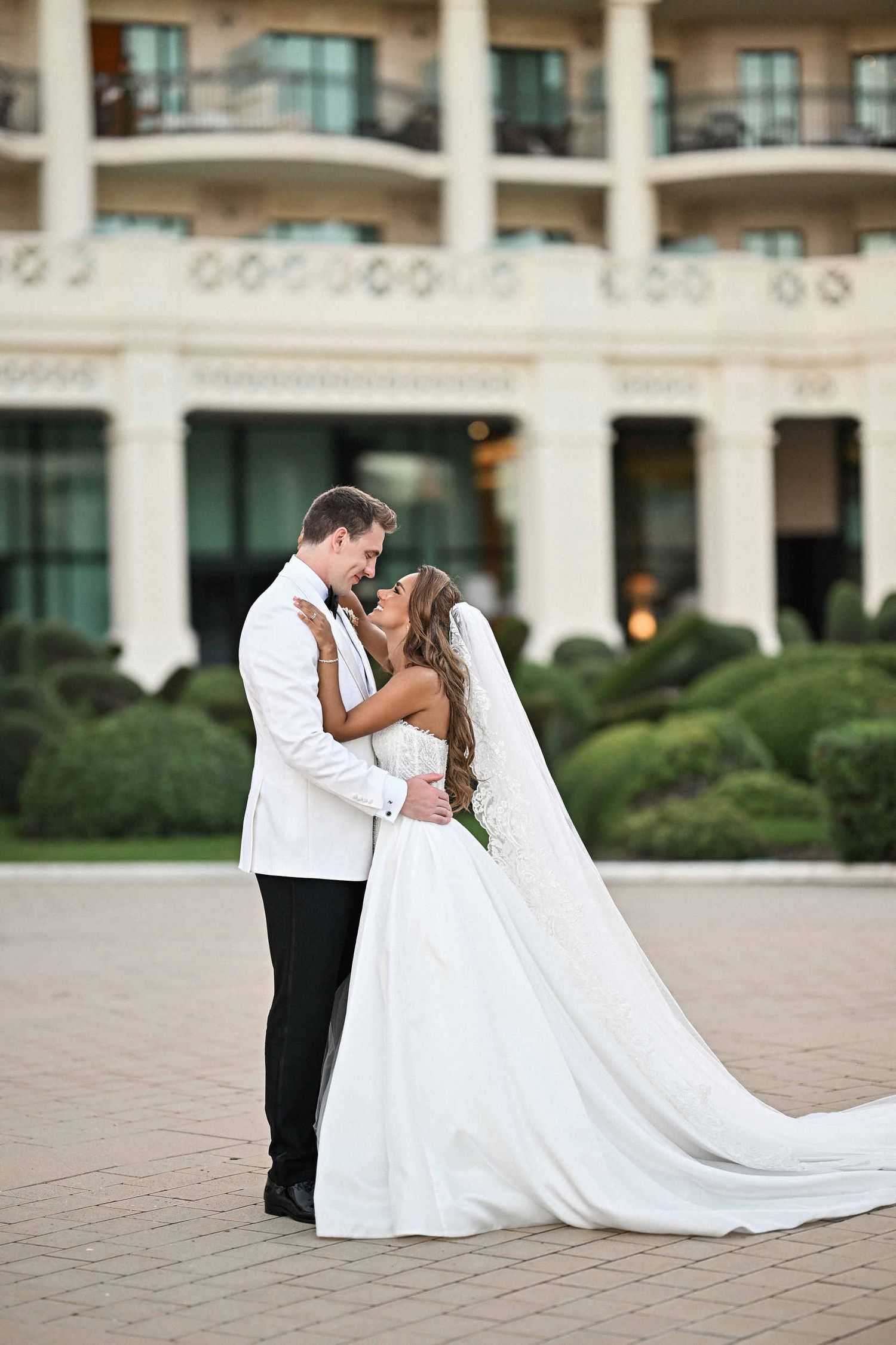 Bride and groom in a white tuxedo sharing a romantic moment in the grand courtyard of Hotel Las Arenas Valencia