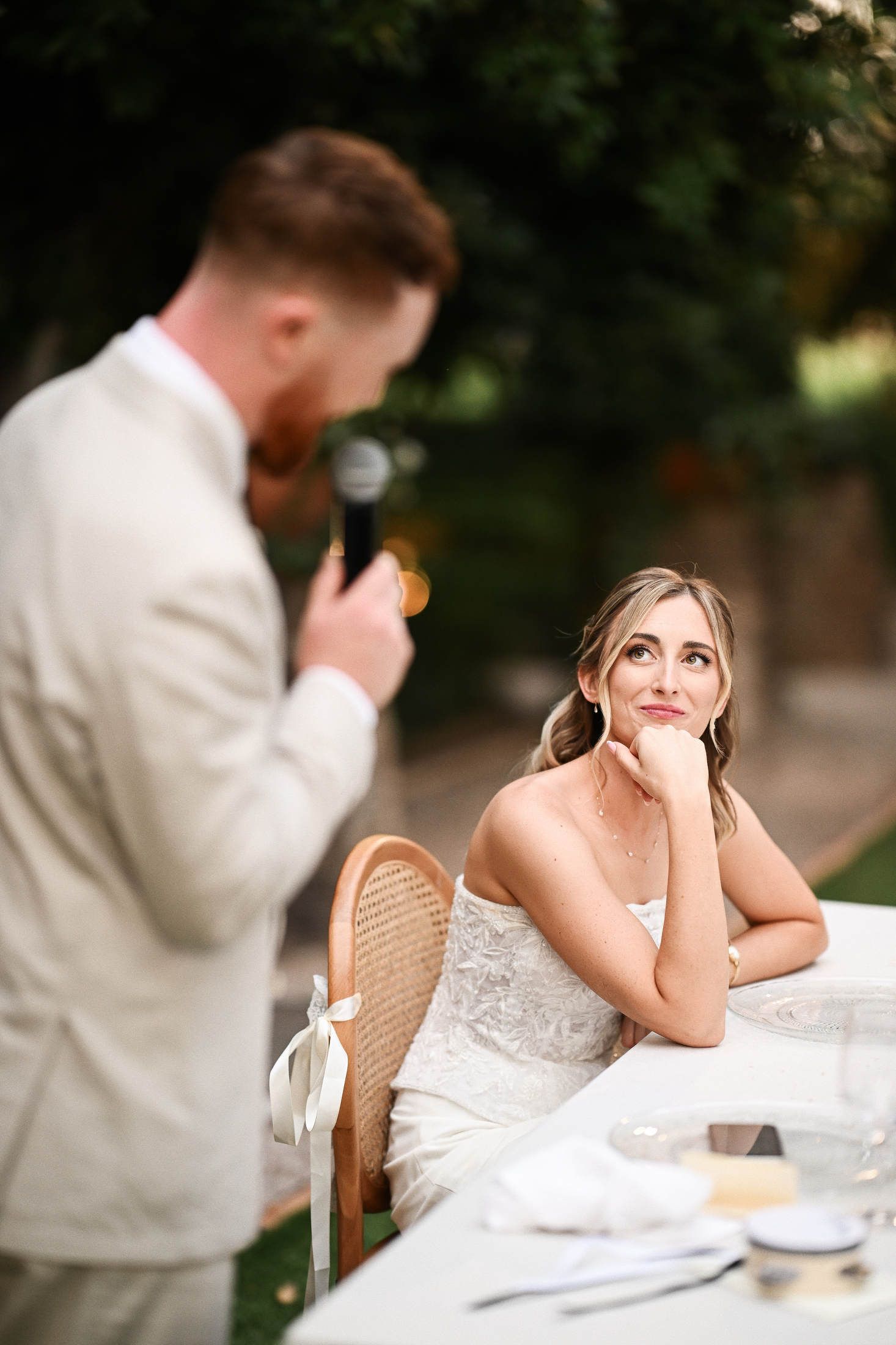 Groom holding a microphone and giving an emotional speech to the bride during an outdoor wedding dinner at Villa Dela.