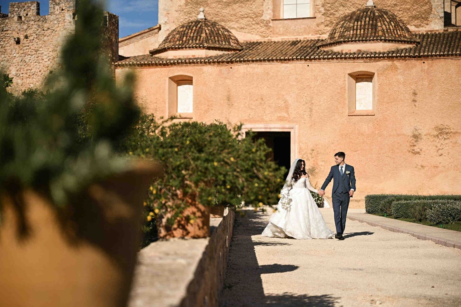 Newlyweds walking along a historic stone alley at Monasterio de Santa María de la Valldigna, capturing the timeless Spanish heritage.