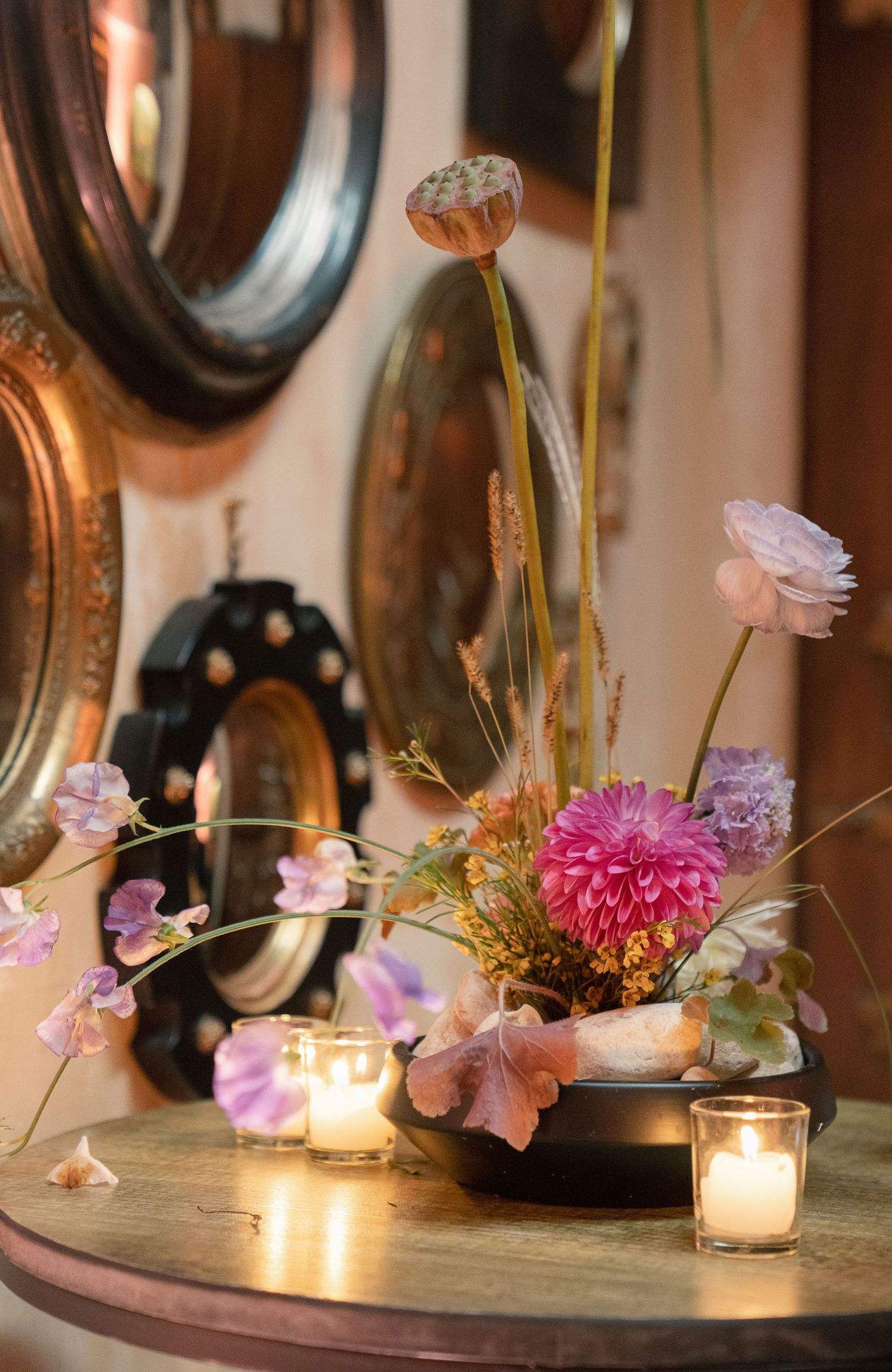 Romantic table setting with pink flowers and candlelight against antique mirrors creates an intimate atmosphere.