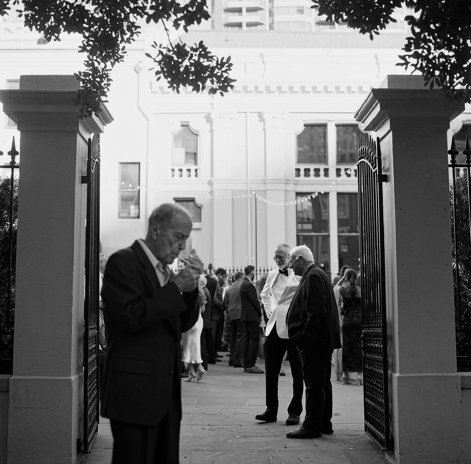 Black and white image of people standing between columns in formal attire.