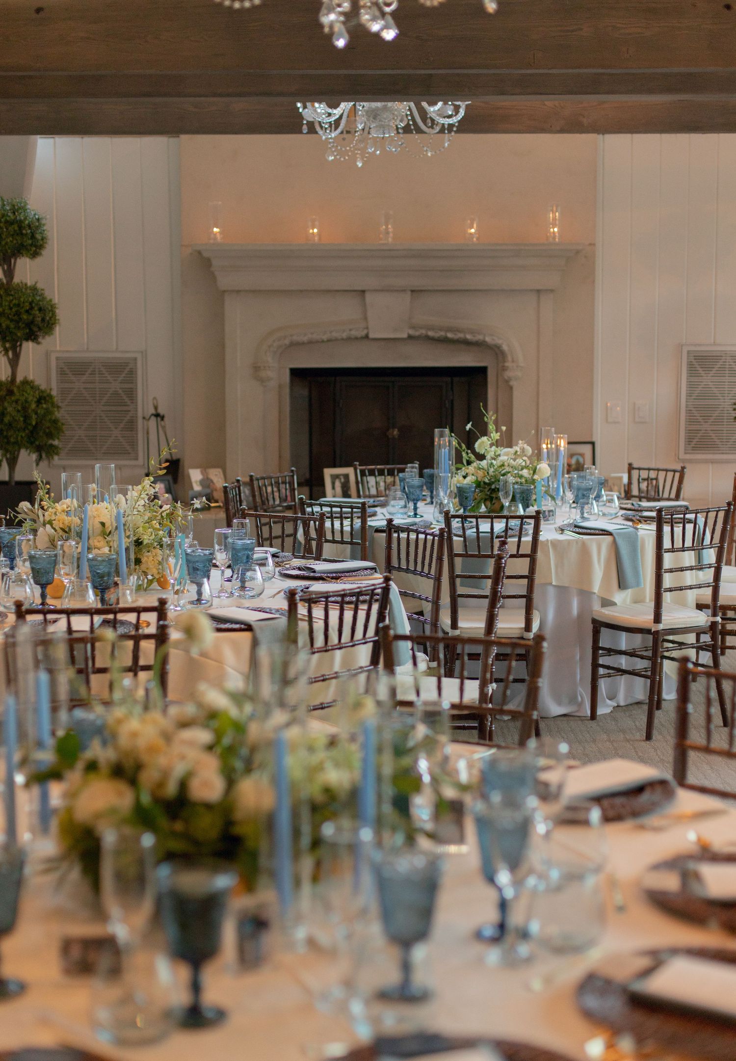 Elegant reception hall with blue and white table settings and a grand fireplace.