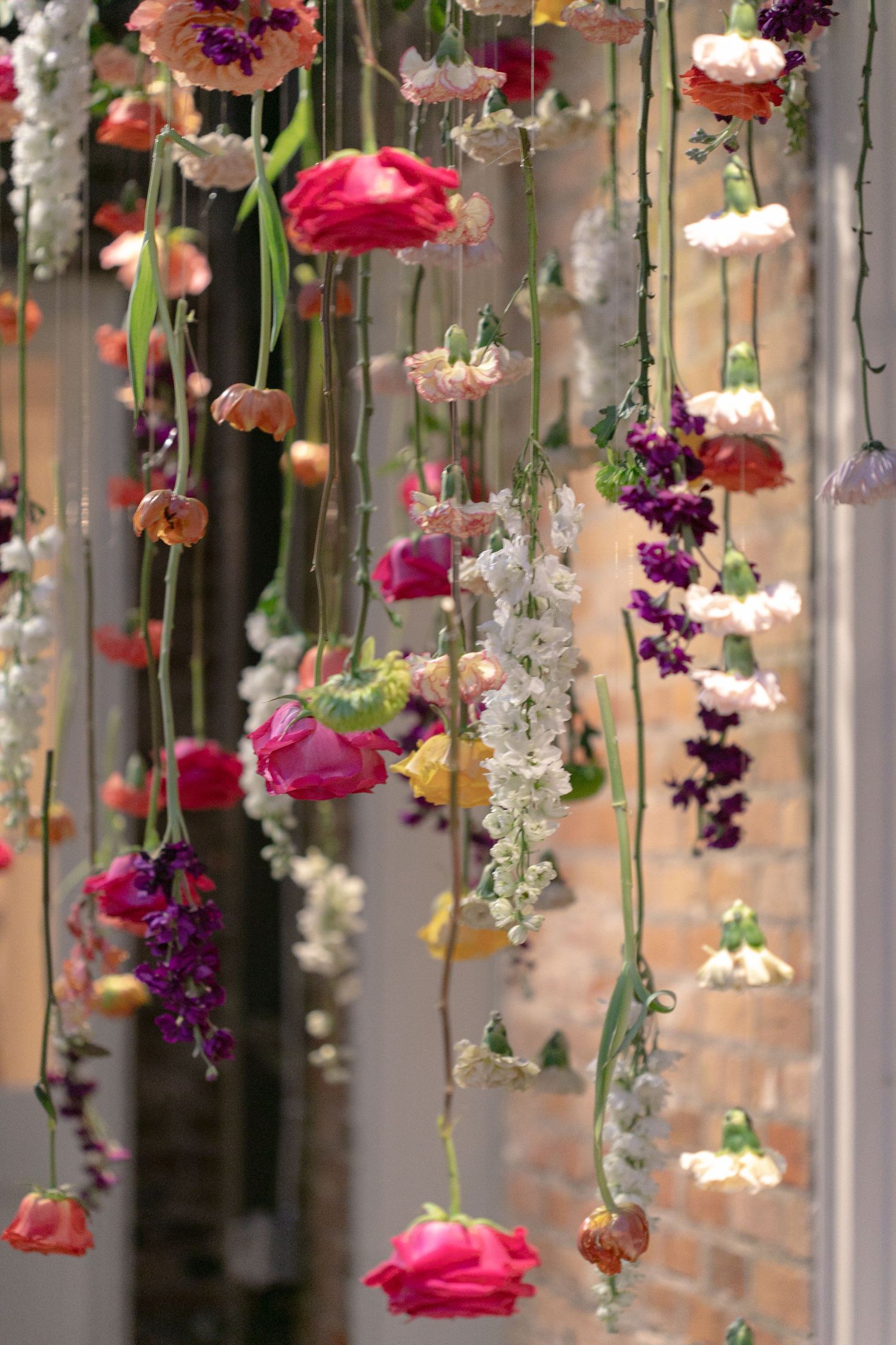 Hanging floral installation with pink and purple flowers suspended from strings creates a romantic garden atmosphere.