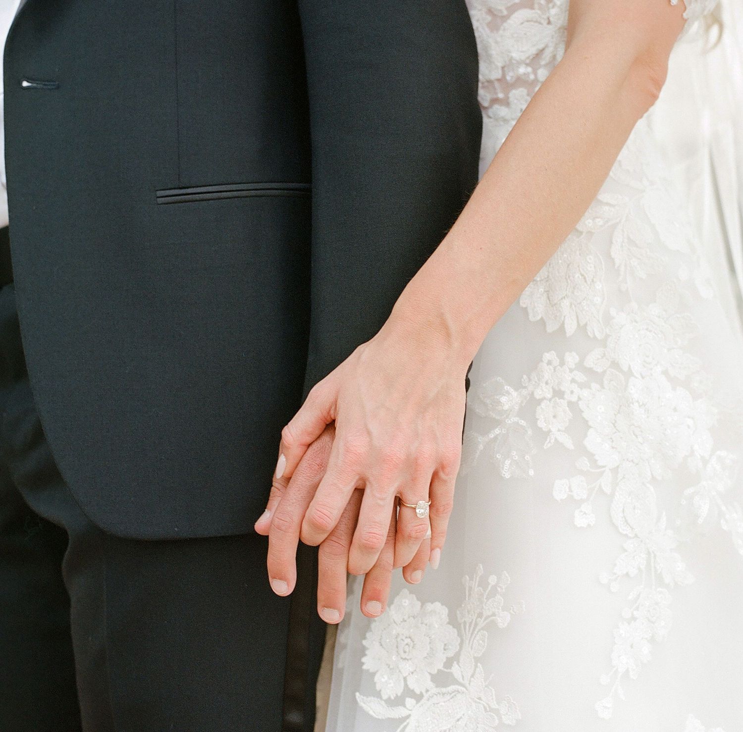 Close-up detail shot of formal wedding attire showing hands and fabric textures.