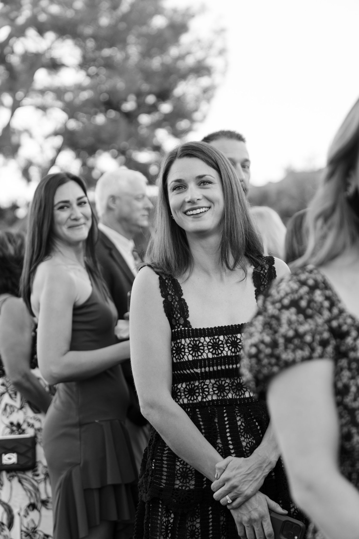 Black and white portrait of wedding guests mingling at an outdoor reception.