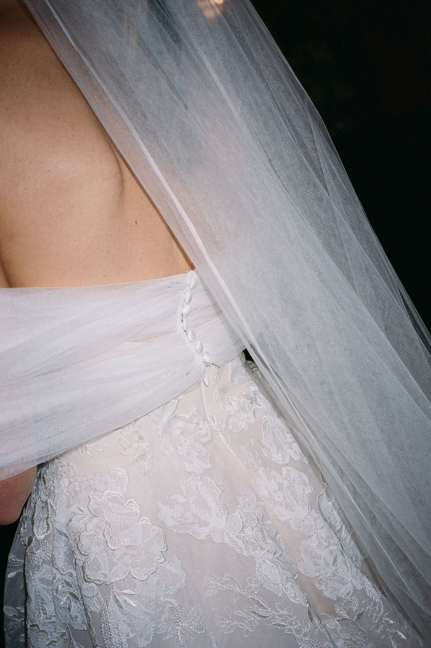 Close-up detail of delicate lace and tulle on white wedding dress.