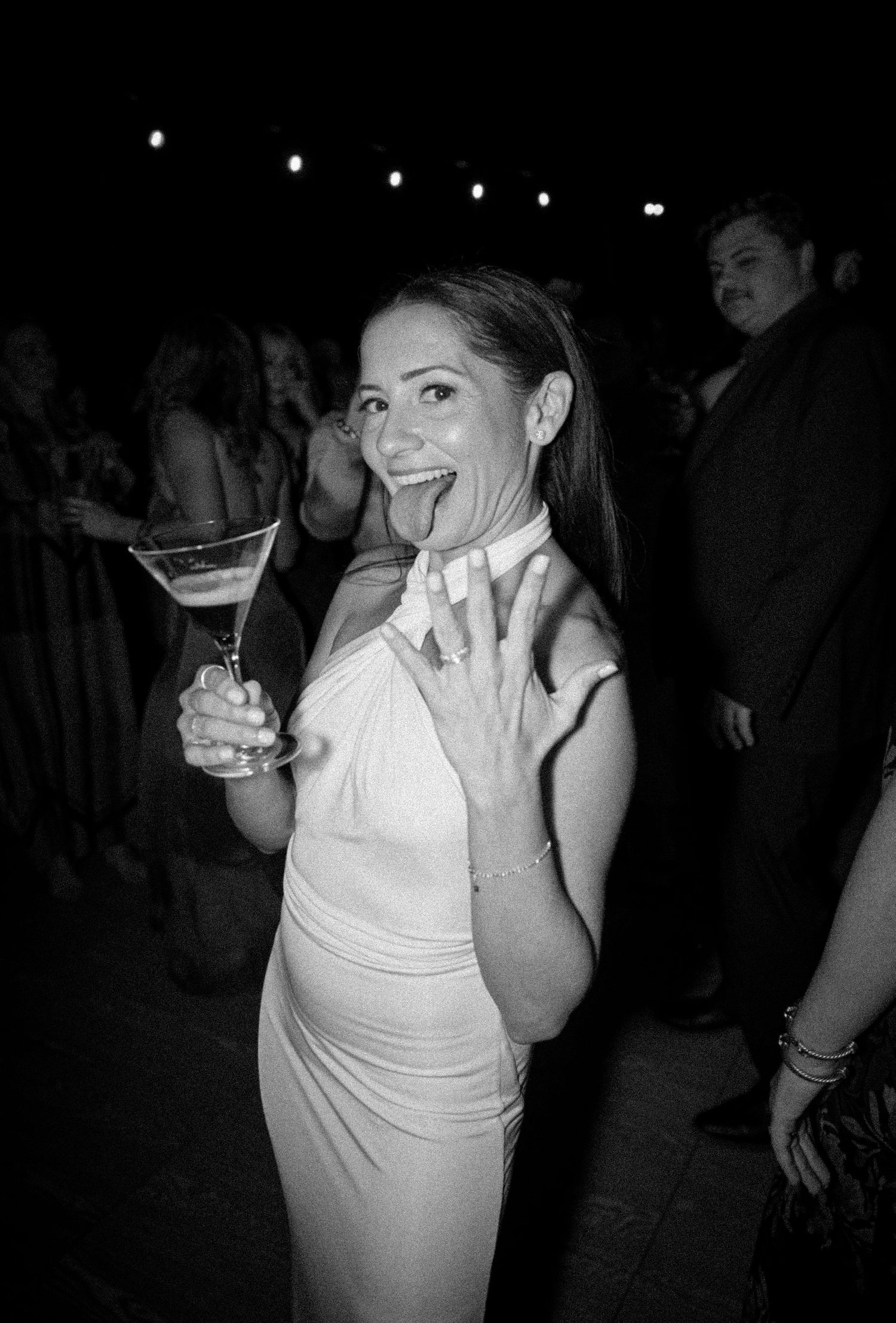 Person in white dress dancing and enjoying themselves at a nighttime celebration.
