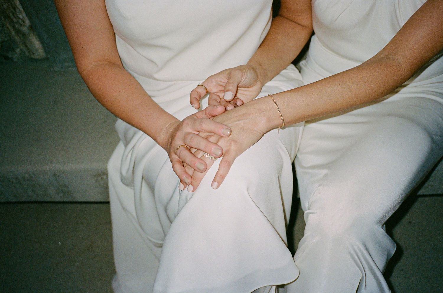 People in white attire sitting close together with hands clasped.