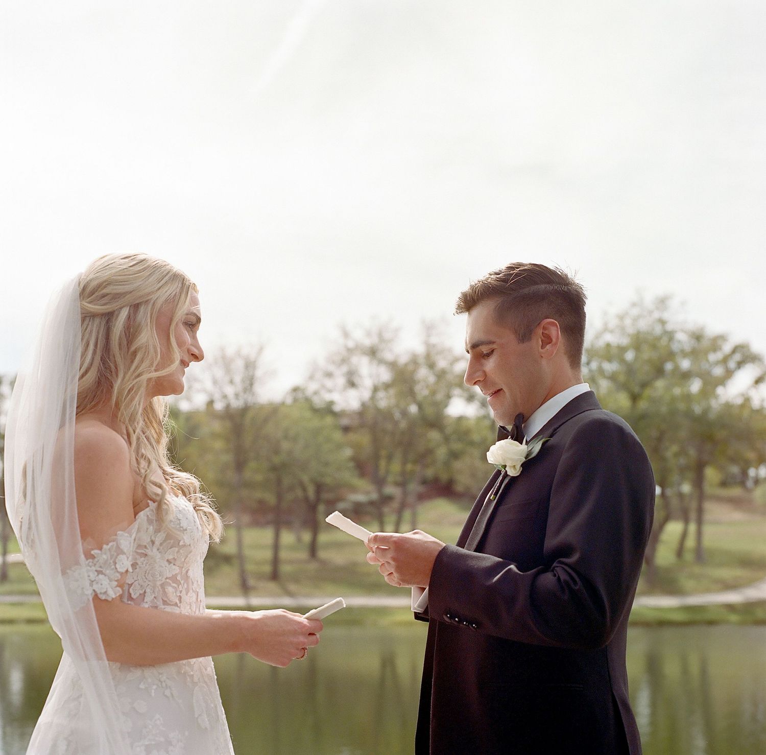Couple exchanging vows on a scenic lakeside dock during their wedding ceremony.