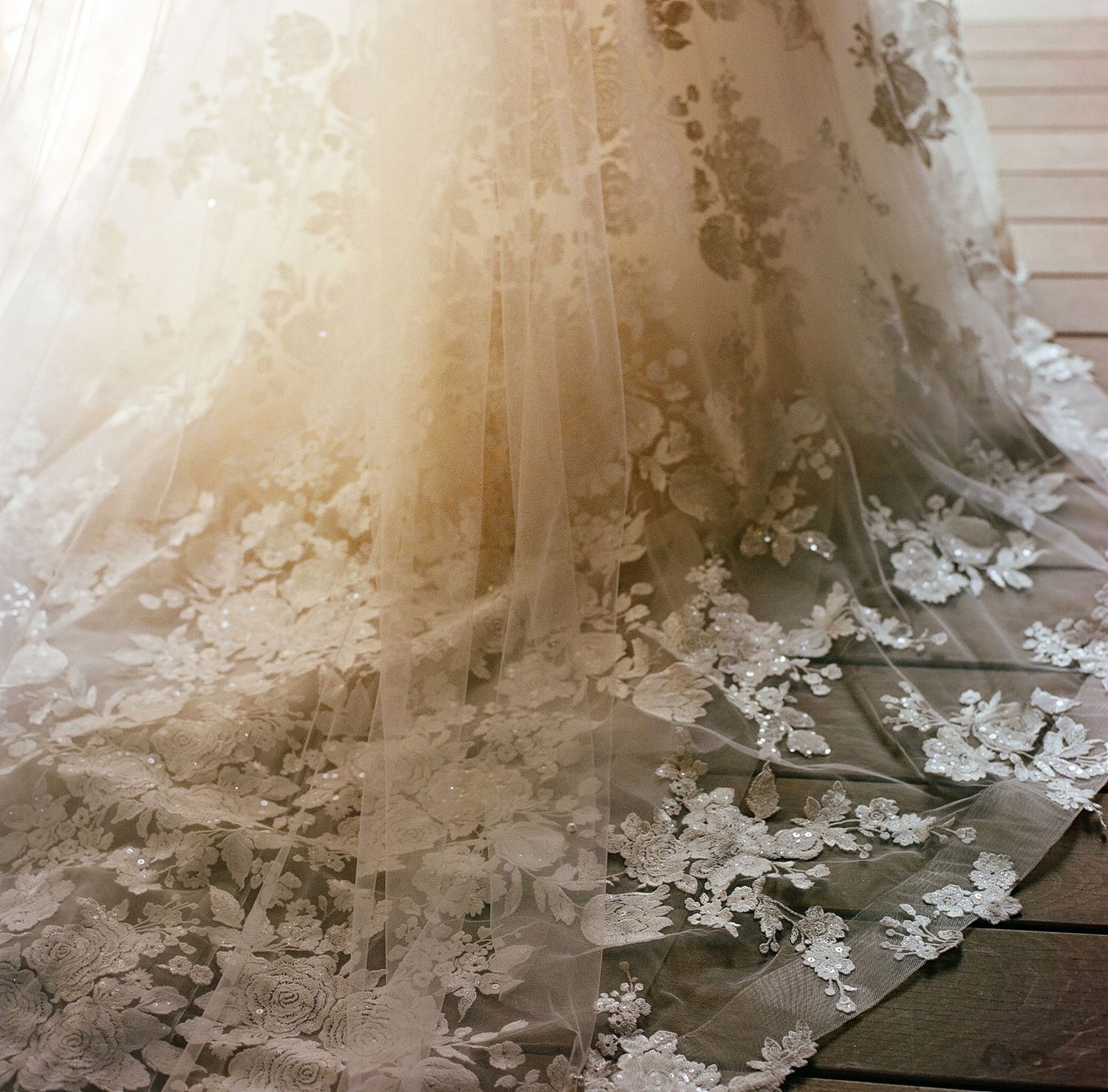 Close-up detail of intricate lace and beading on a wedding dress train.