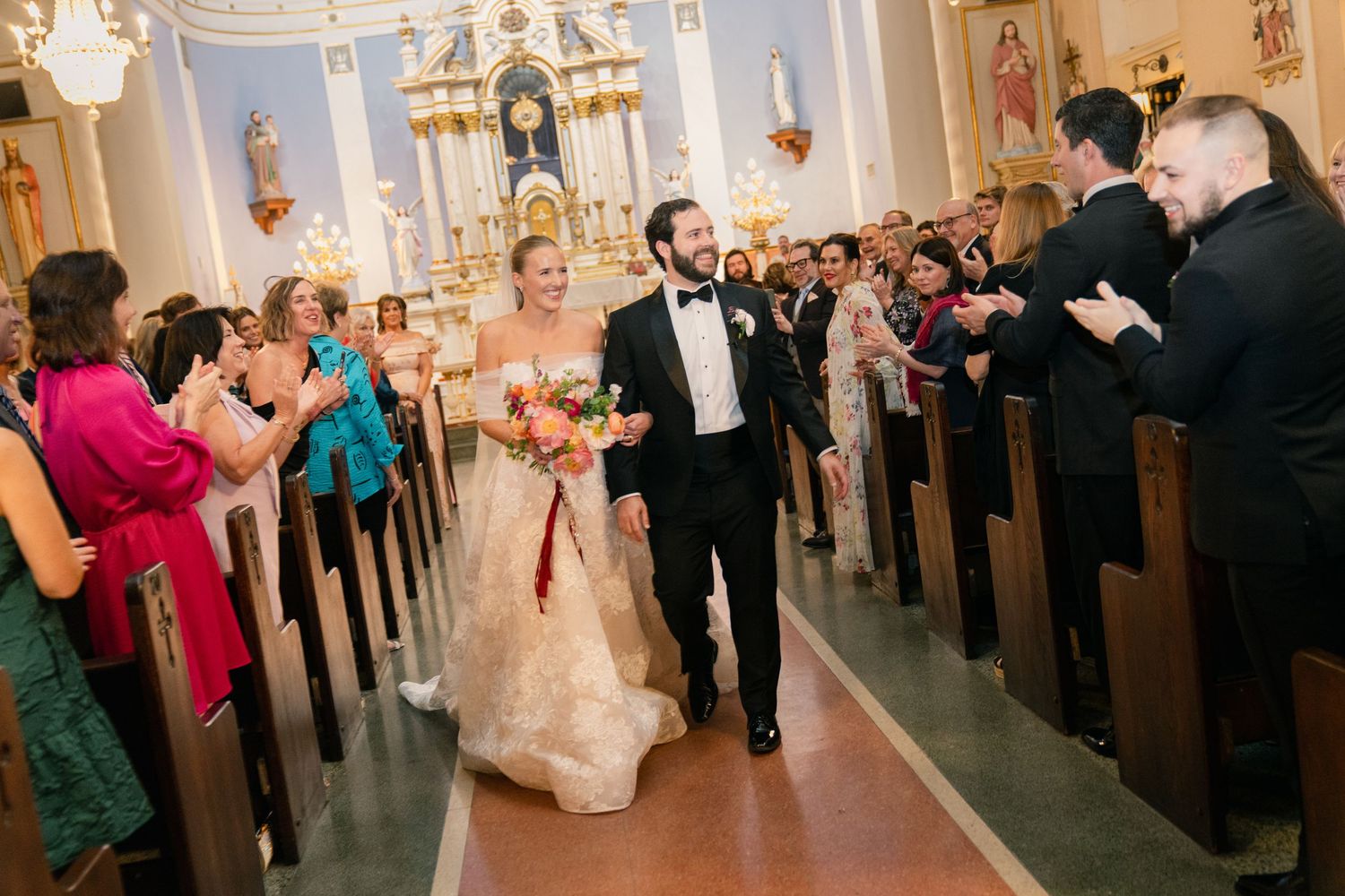 Wedding guests celebrate in church pews during a joyful reception.