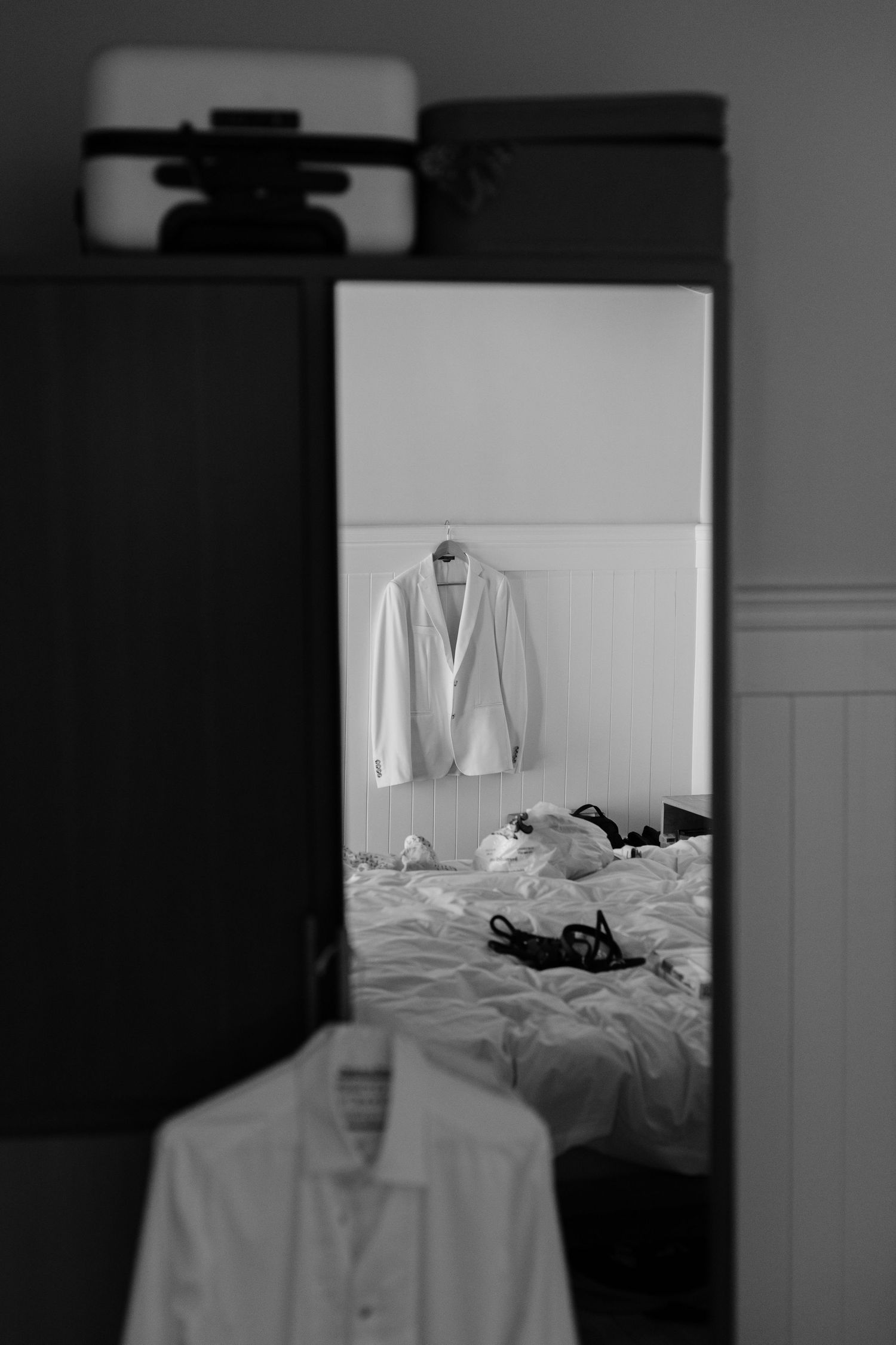 White dress shirts hanging in a room reflected in a mirror.