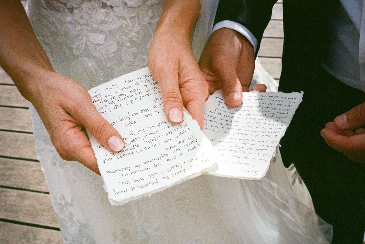 Close-up shots of hands holding handwritten wedding vows on paper.