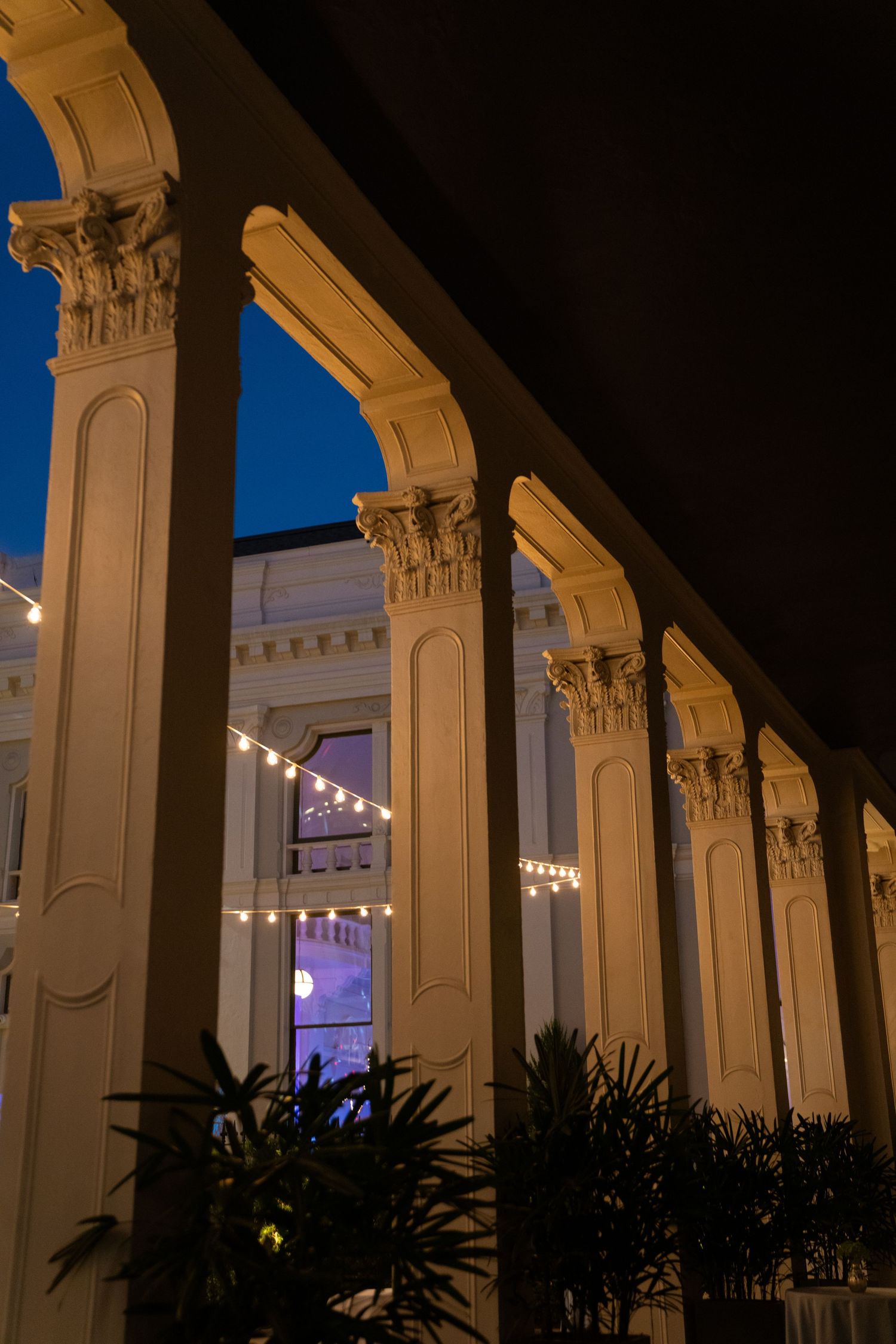 Ornate stone columns lit at dusk with string lights creating romantic ambiance.