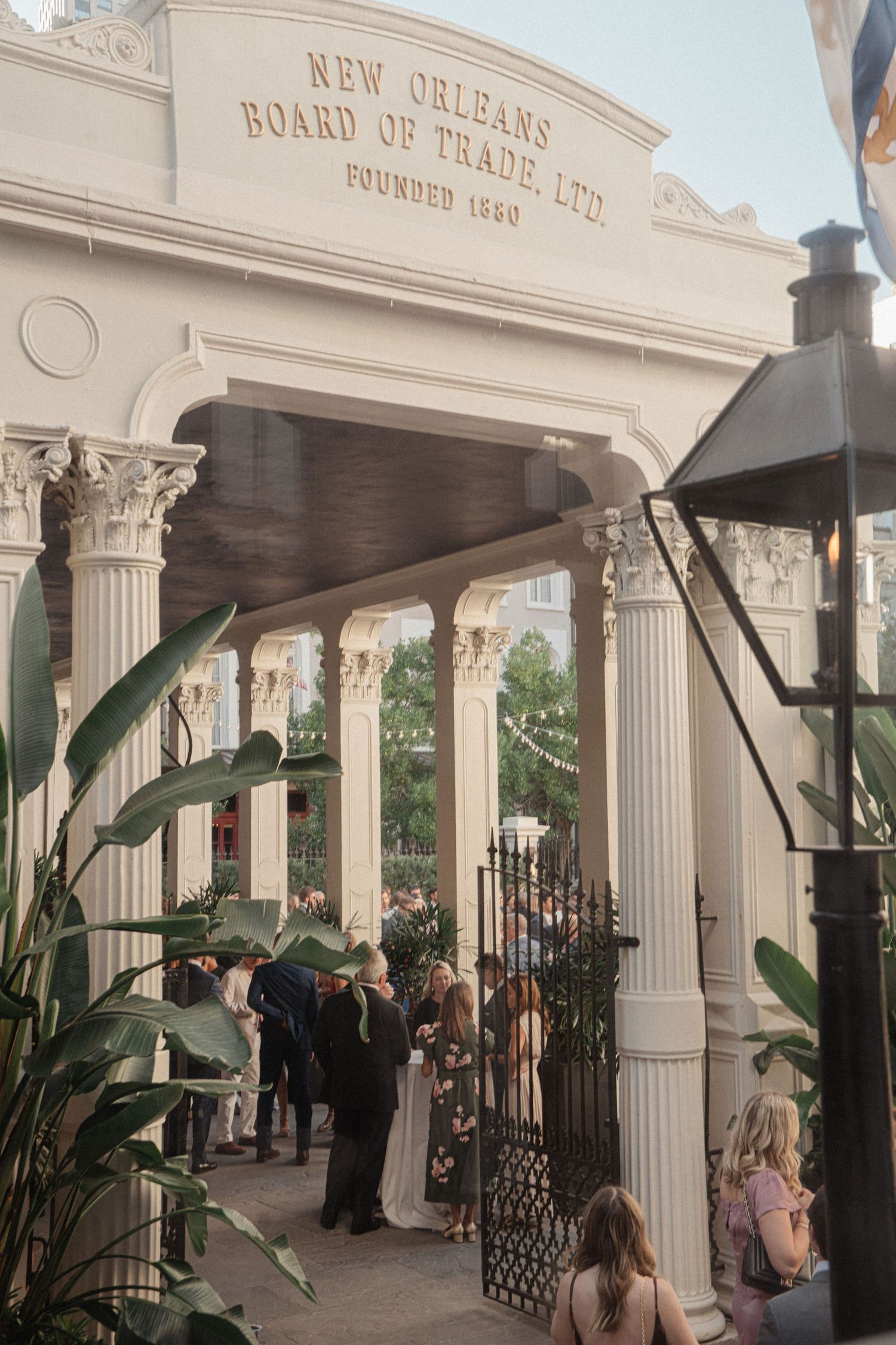 Historic New Orleans Board of Trade building entrance with columns and tropical plants.