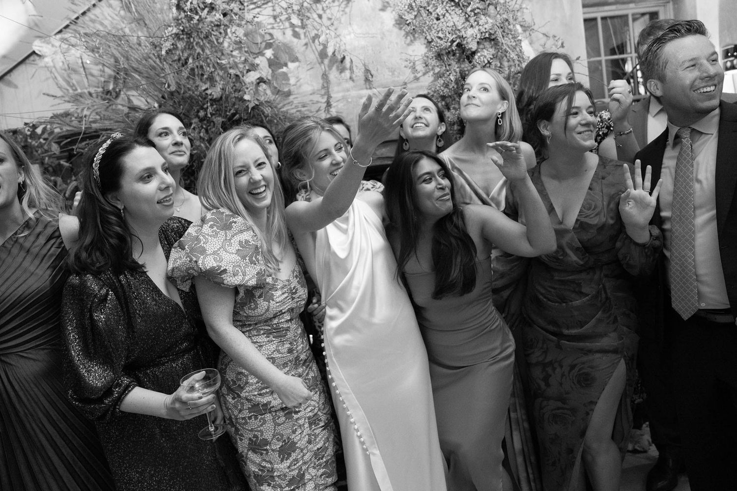 Black and white photo capturing candid moments of celebration at a wedding party.
