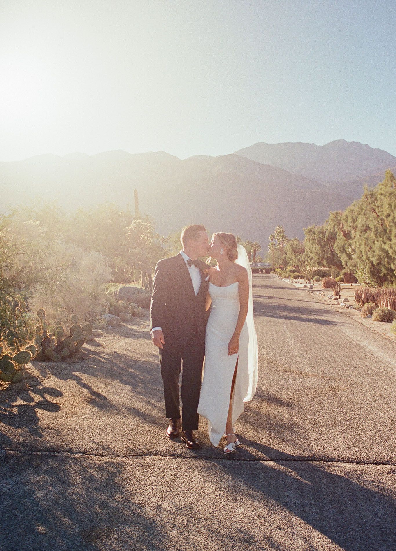Couple walking together at sunset with mountains and desert landscape in background.